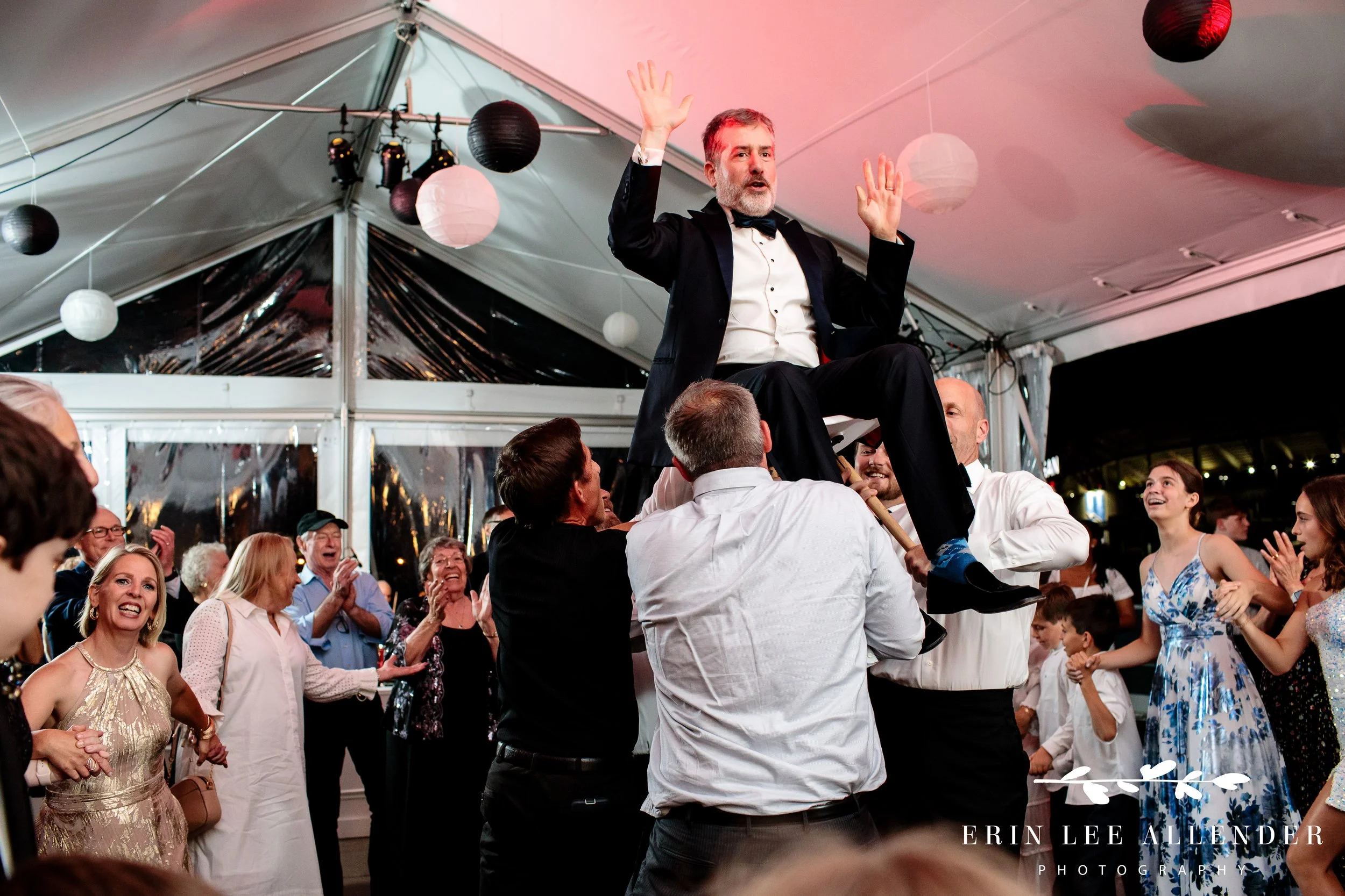 Father lifted in chair during horah at Nashville Bar Mitzvah rooftop reception.