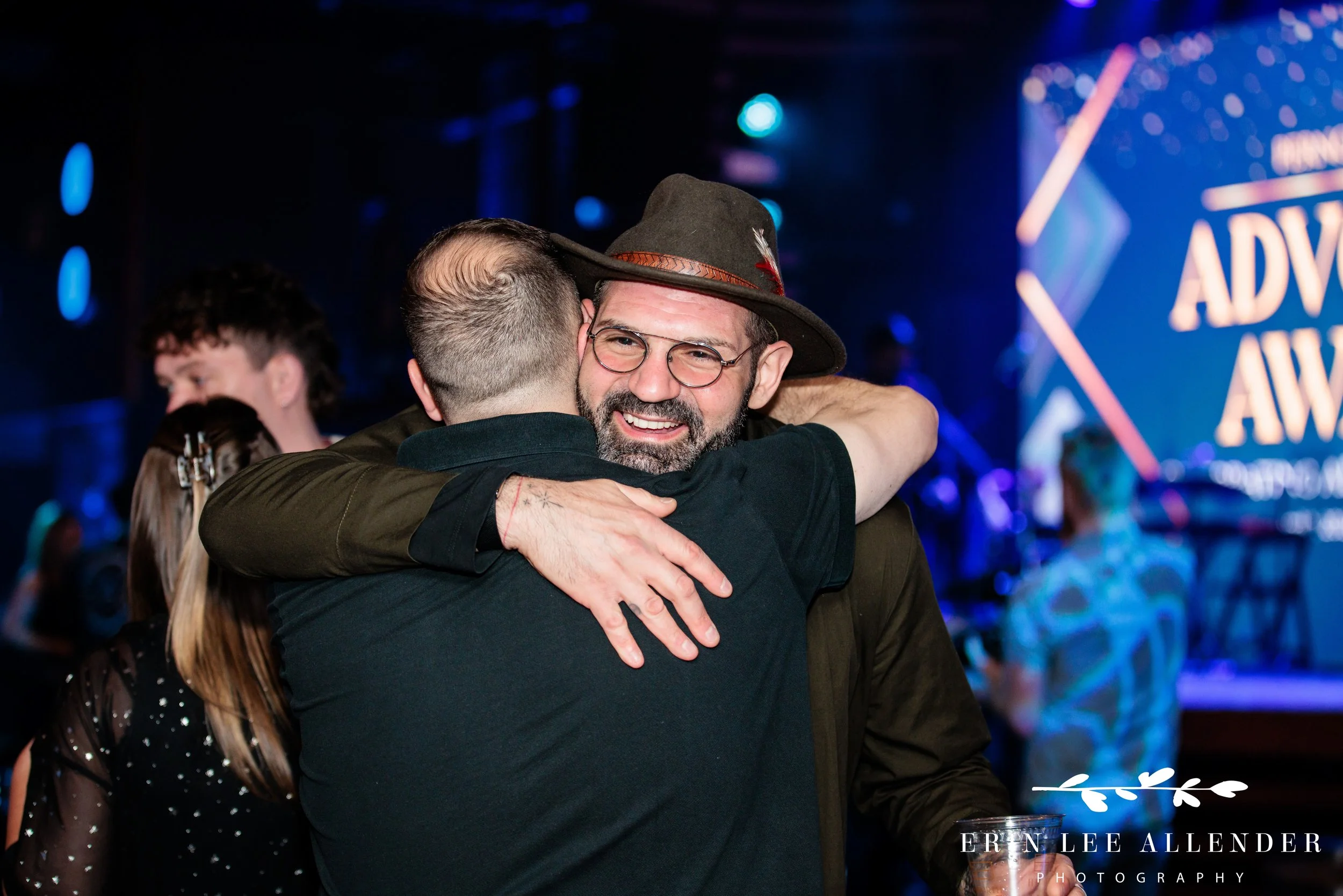 Nashville corporate event photographer — advocacy award winner receiving a hug after award, Woolworth Theatre Nashville