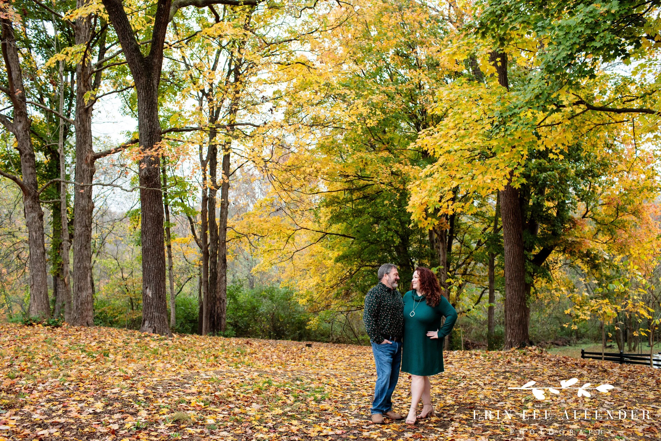 Wide shot of husband and wife standing among fall leaves during a Nashville family photography session at Ellington Agricultural Center