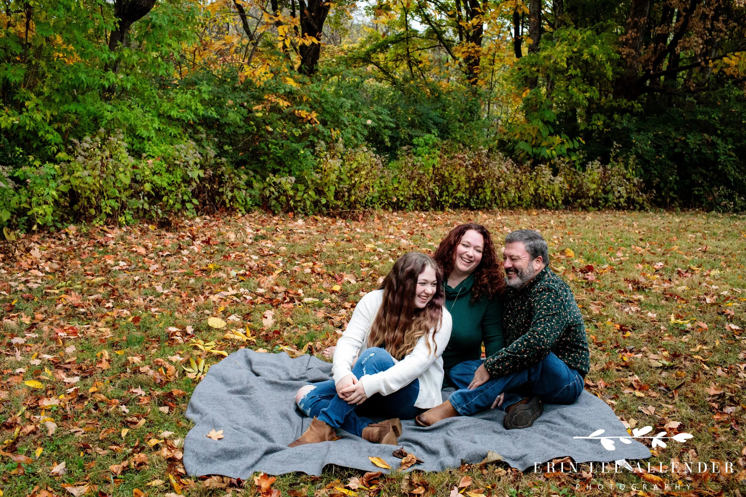 Family sitting together on a blanket laughing during a Nashville family session at Ellington Agricultural Center