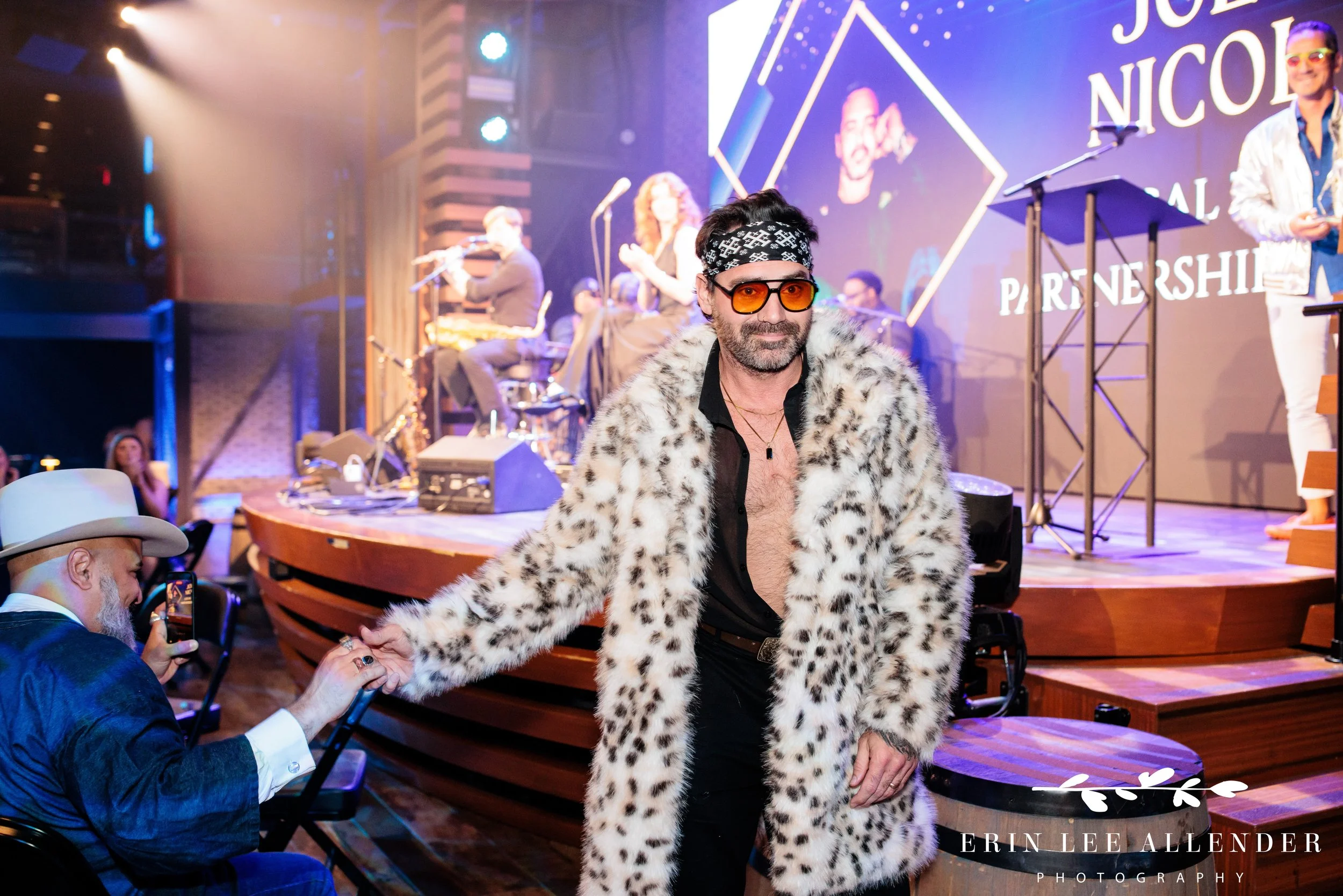 Nashville corporate event photographer — award winner in faux fur coat high-fiving ambassadors on way to stage, Woolworth Theatre Nashville