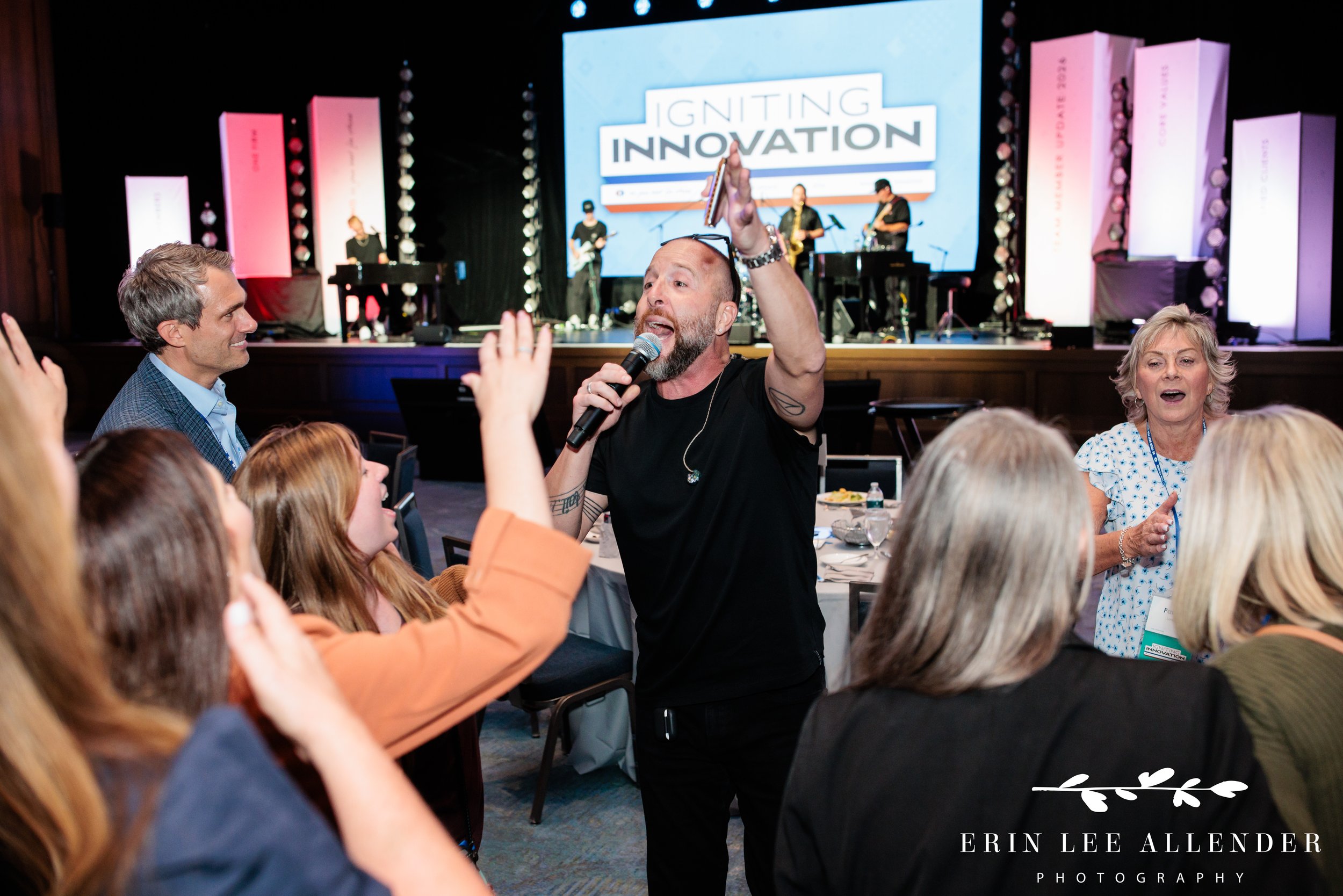 Nashville corporate event photography of a Music City Dueling Pianos performer on the floor getting guests to sing during RubinBrown's awards dinner at Opryland