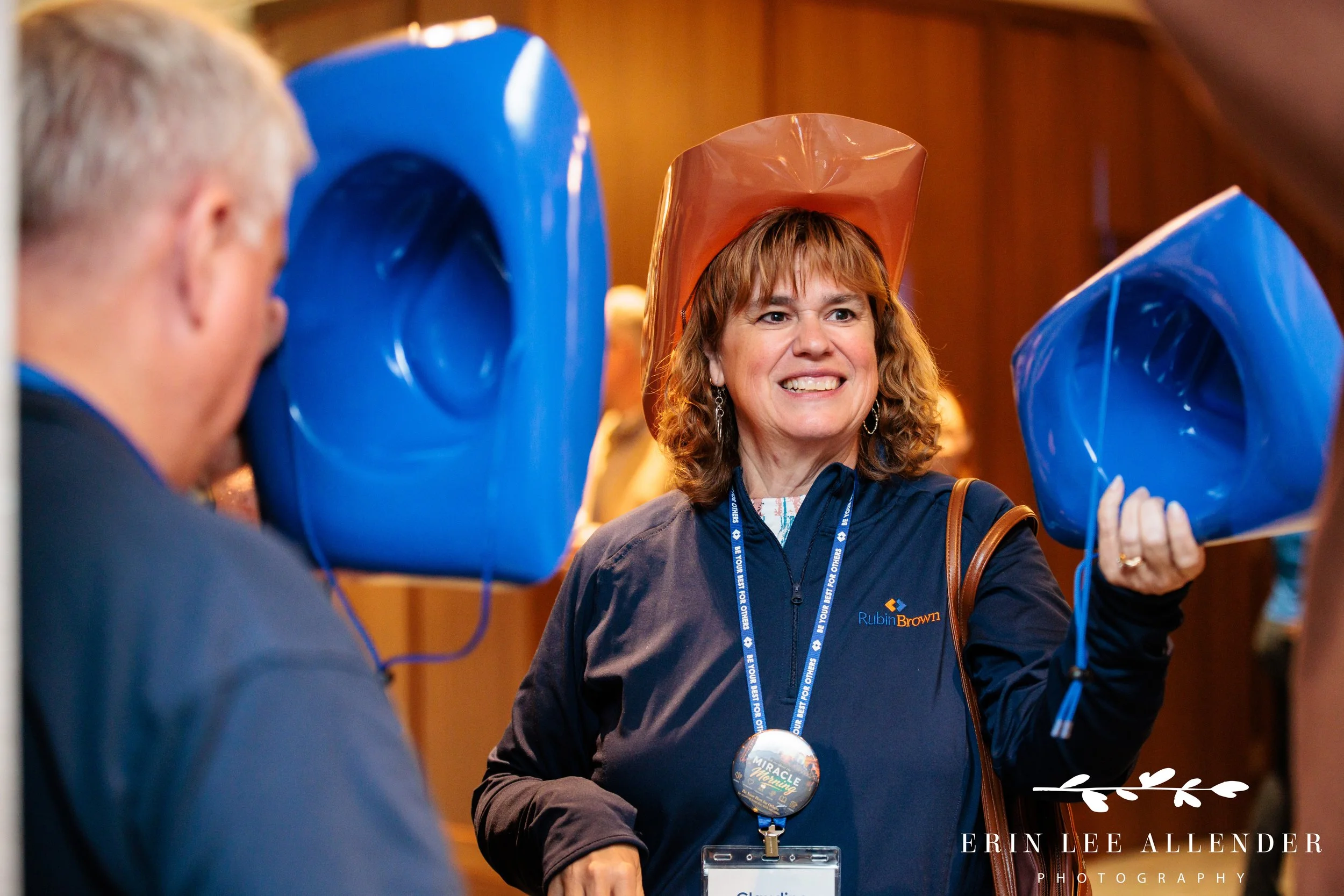 Nashville corporate event photographer capturing an attendee handing out cowboy hats in RubinBrown's colors during their conference at Gaylord Opryland Resort