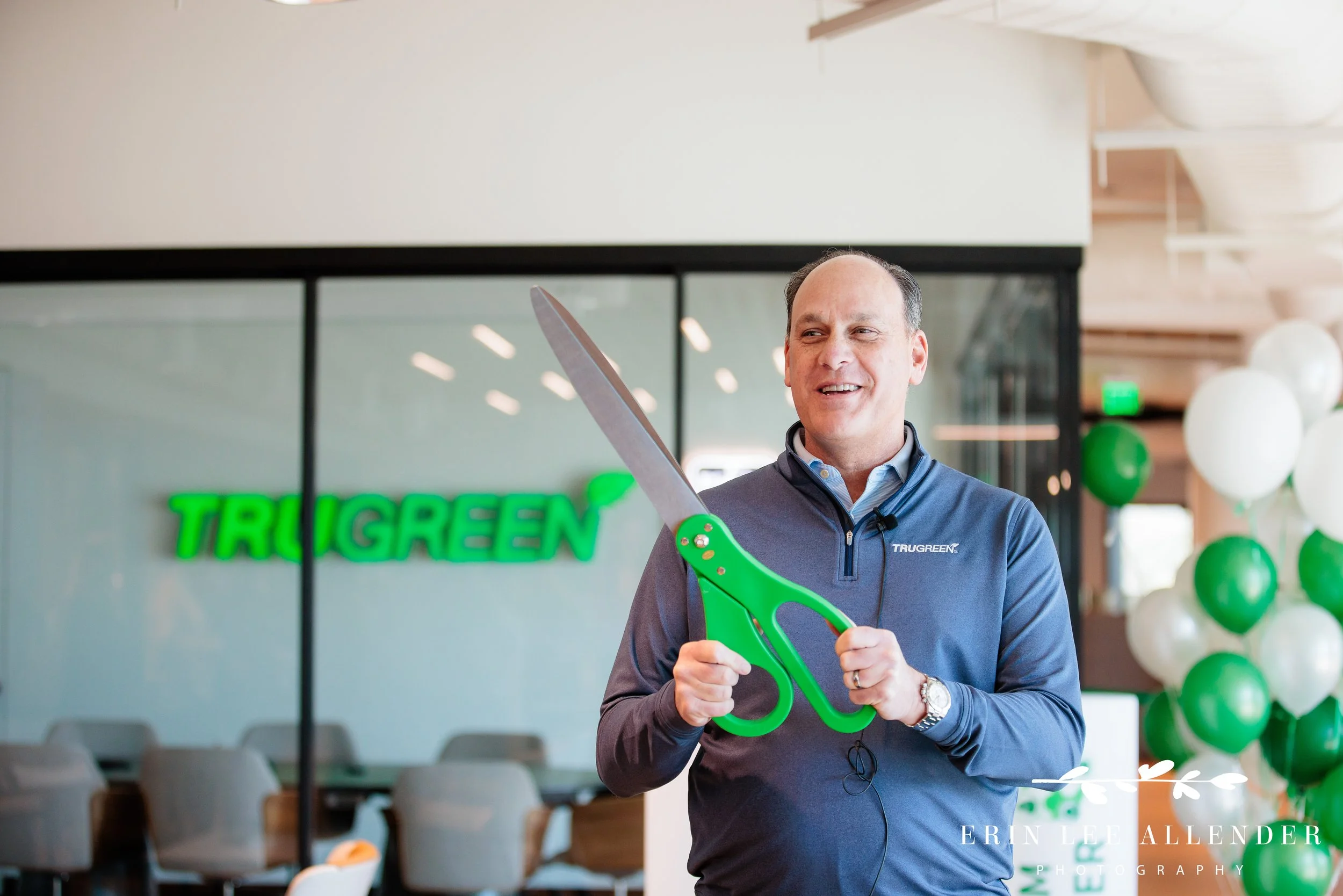 Nashville corporate photographer — CEO holding oversized green scissors at TruGreen office expansion ribbon cutting
