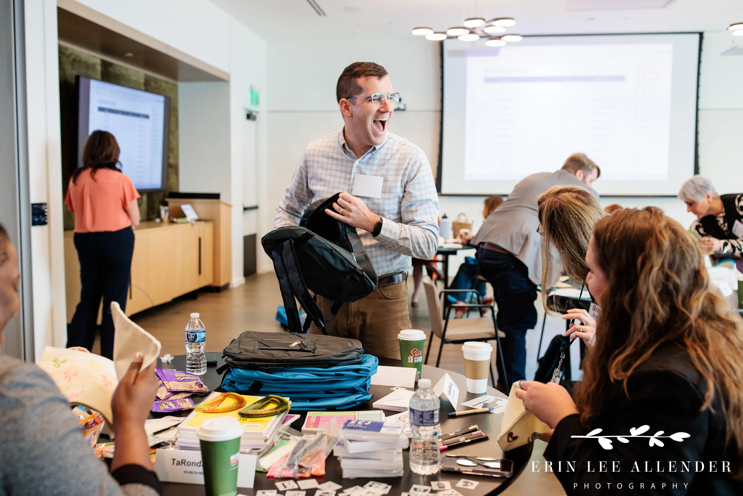 Nashville corporate event photographer capturing a group laughing together while filling backpacks for local students.