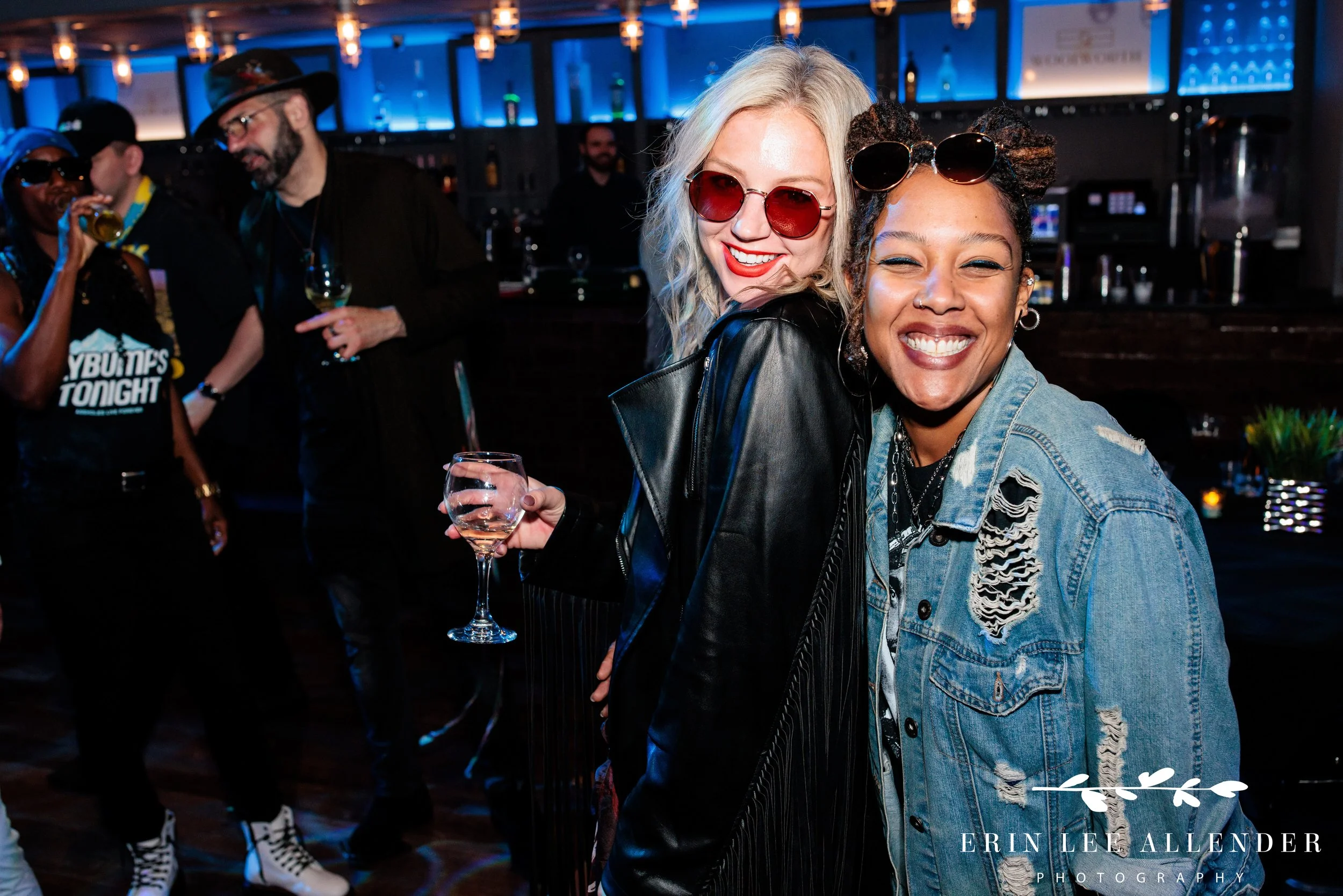 Nashville corporate event photographer — two ambassadors with cocktails hugging and smiling at camera, Woolworth Theatre Nashville