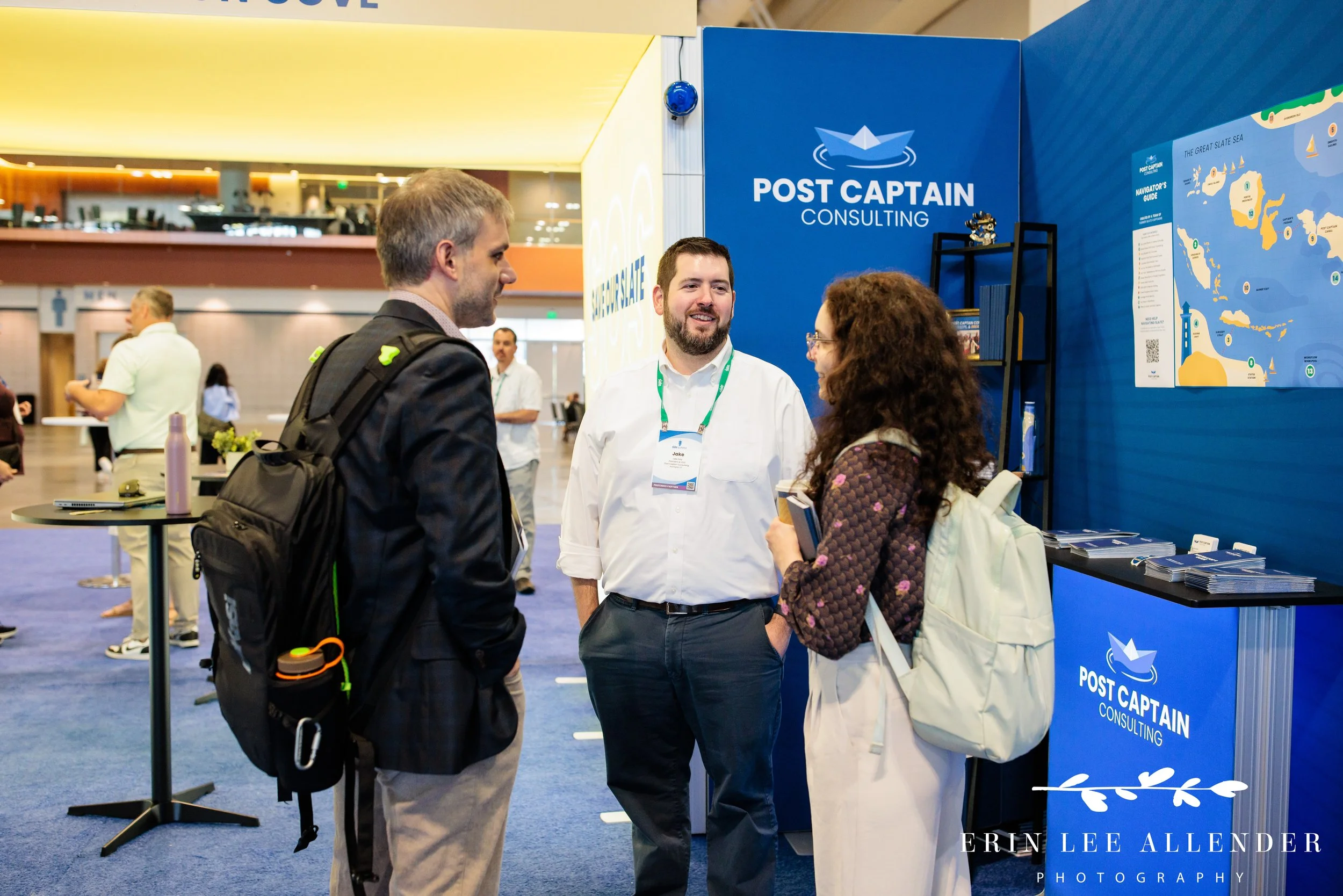 Nashville corporate event photography — Post Captain consultant talking with an attendee in front of their branded booth backdrop at the Slate Summit