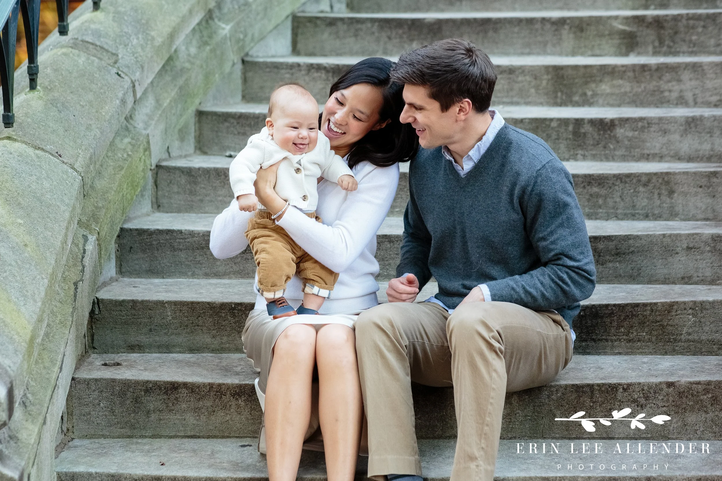 Parents laughing with baby in their arms during a Vanderbilt outdoor family session.