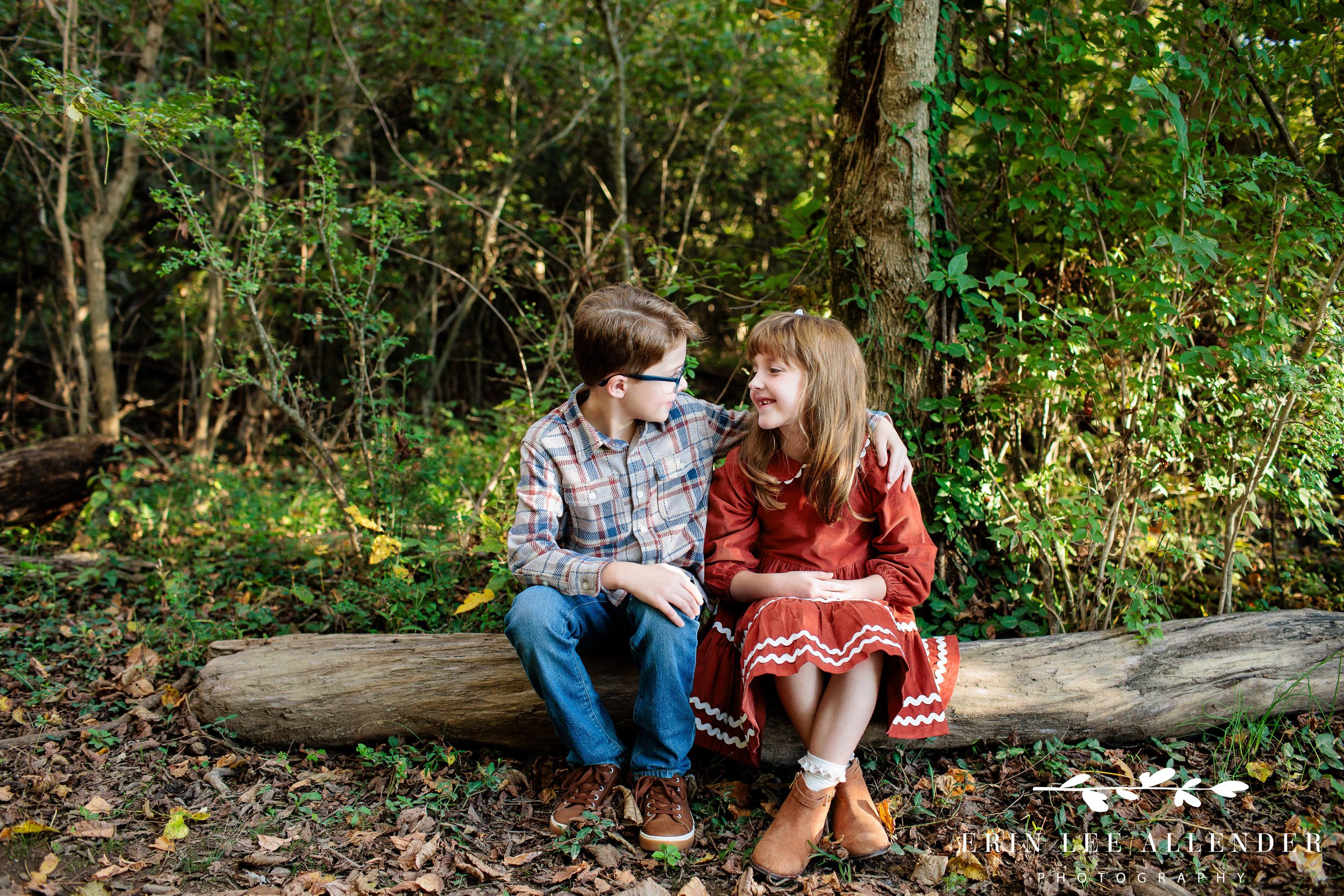 Nashville family photography — brother and sister sitting together on a log along the wooded trail at Walton Ferry Arboretum