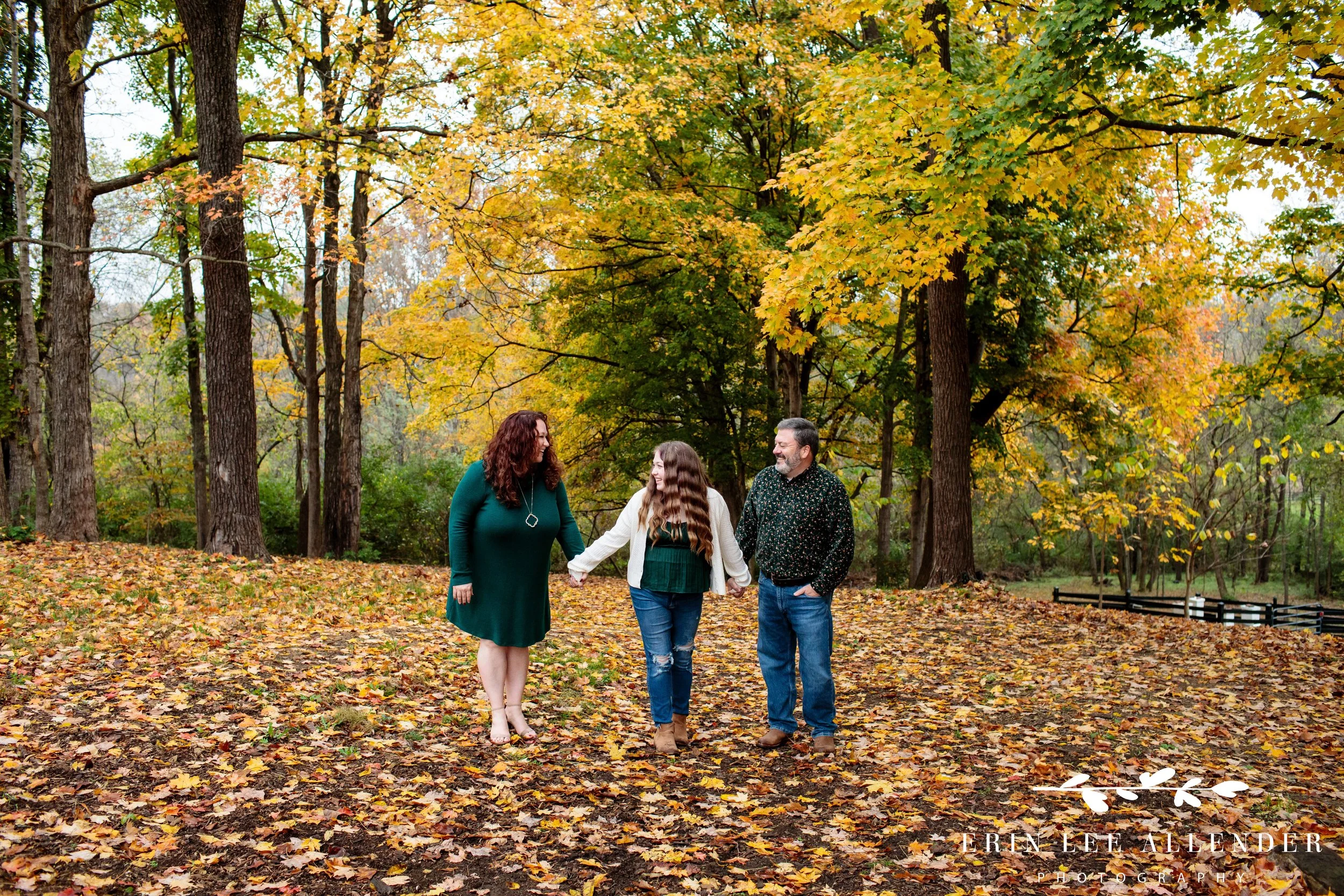 Wide shot of husband and wife standing among fall leaves during a Nashville family photography session at Ellington Agricultural Center