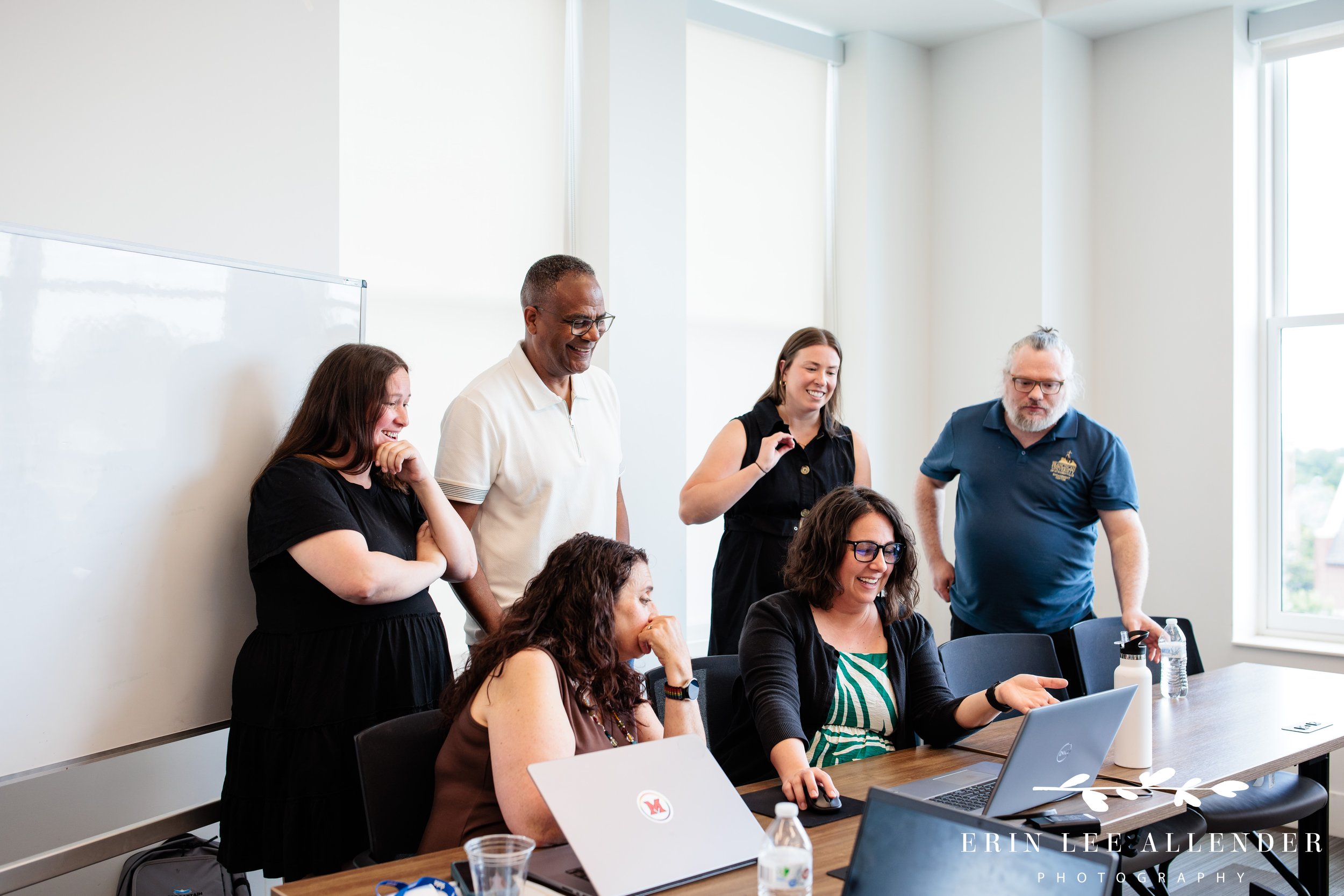 Nashville corporate event photography — college clients gathered around a laptop reviewing a Slate solution at Post Captain's Unstuck event