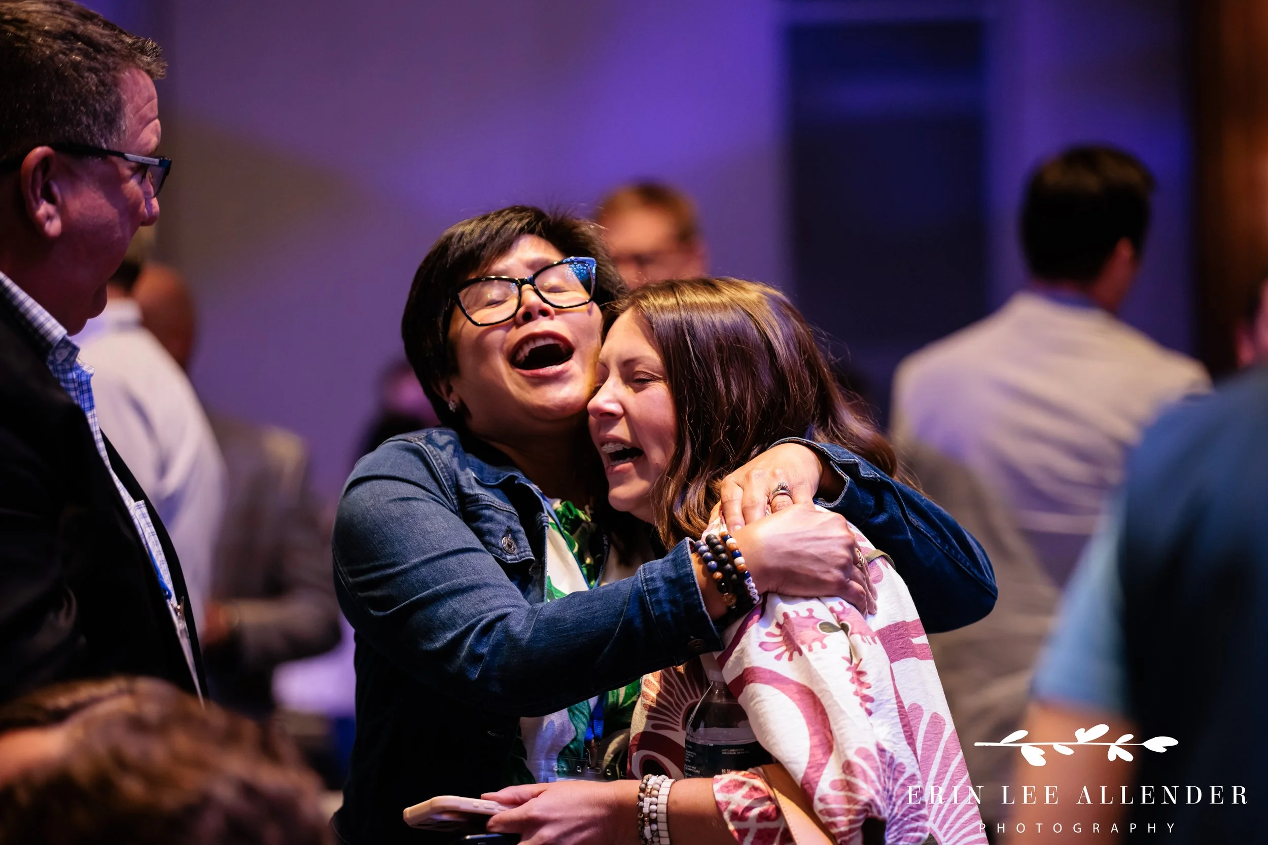 Nashville corporate event photographer capturing guests hugging and singing along during Music City Dueling Pianos at RubinBrown's awards dinner at Gaylord Opryland Resort