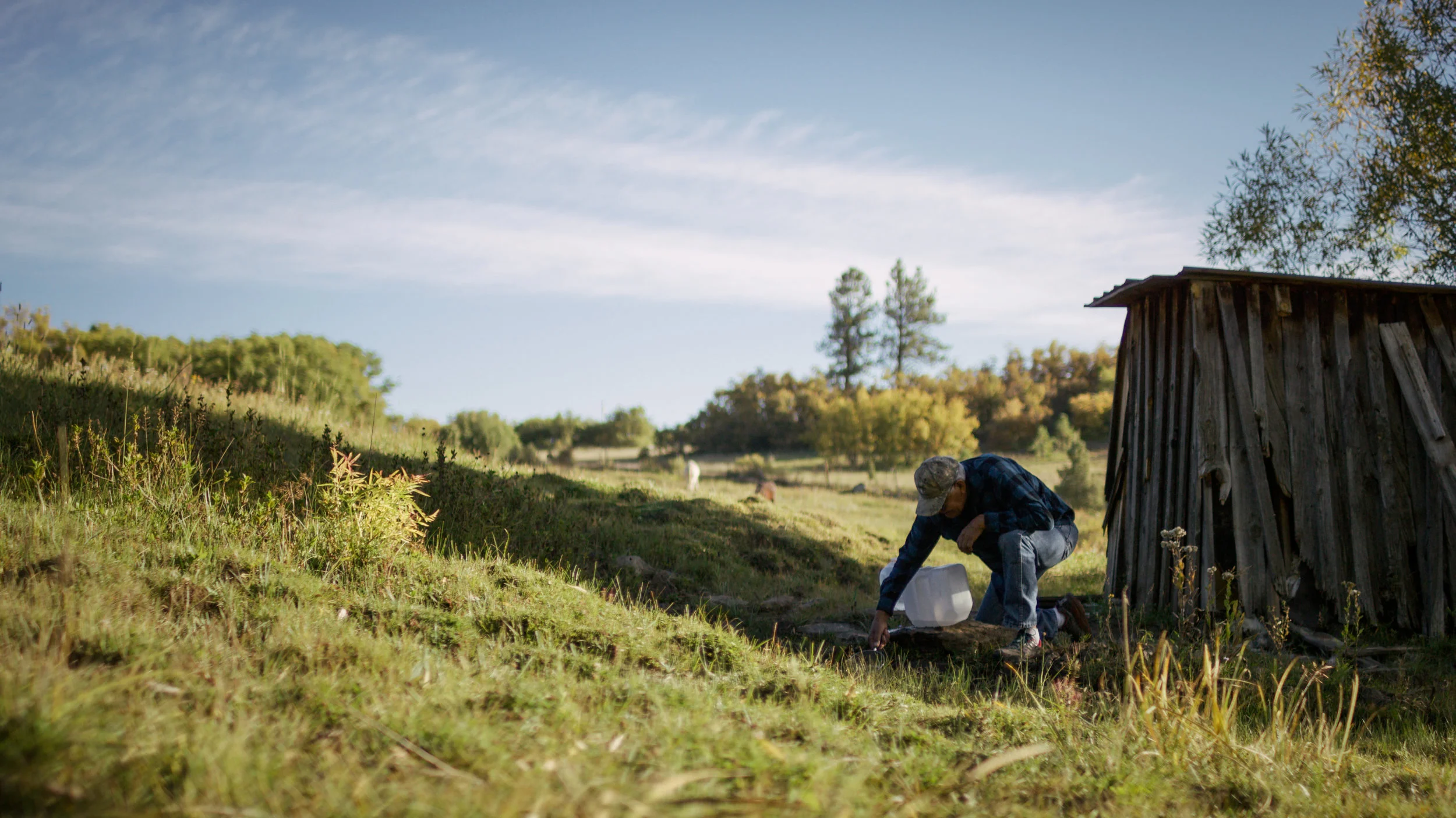 Tito Naranjo collects water from a spring on his property in Mora, NM.