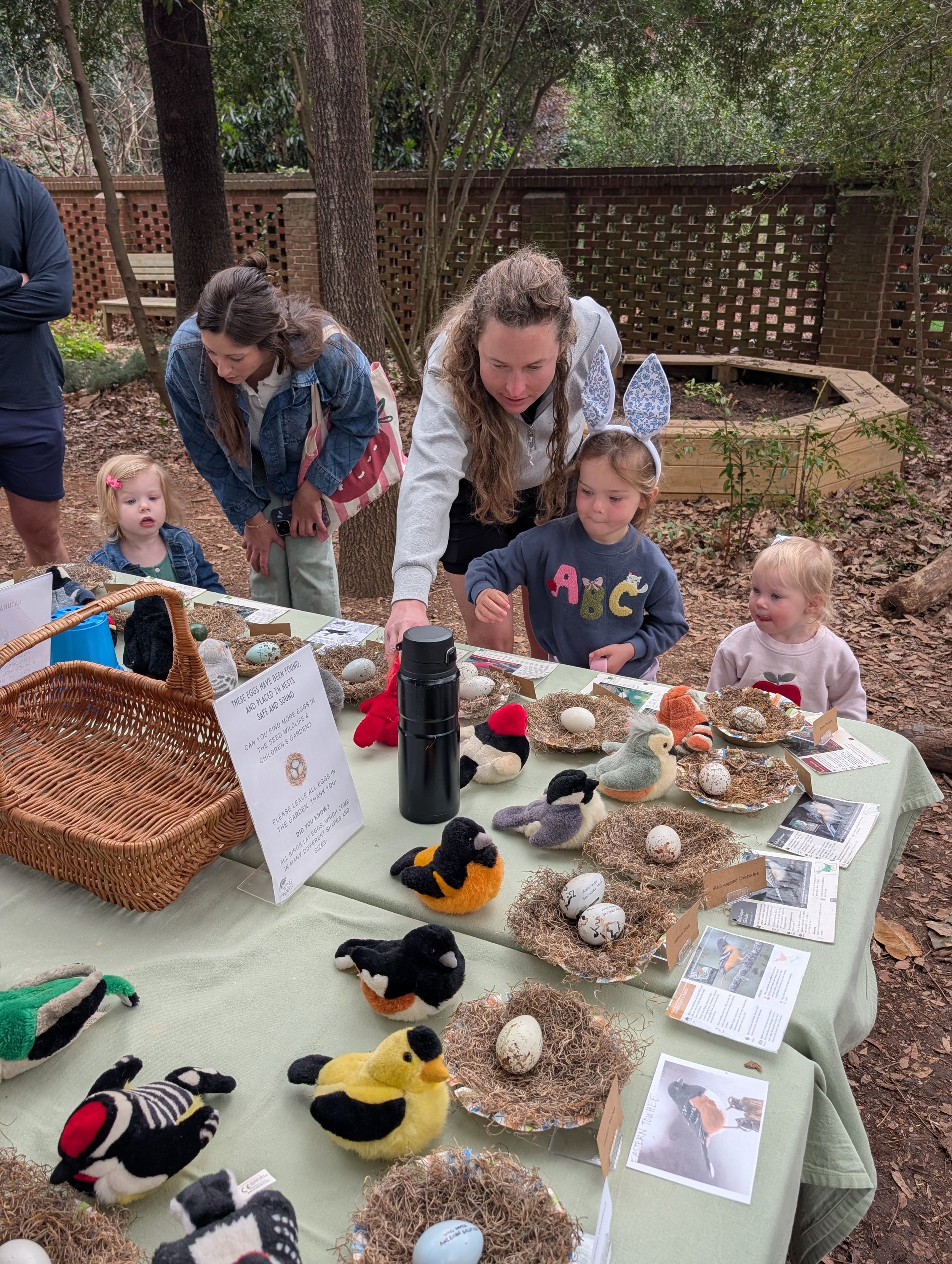 Children standing around a table with fake birds, nests and eggs.