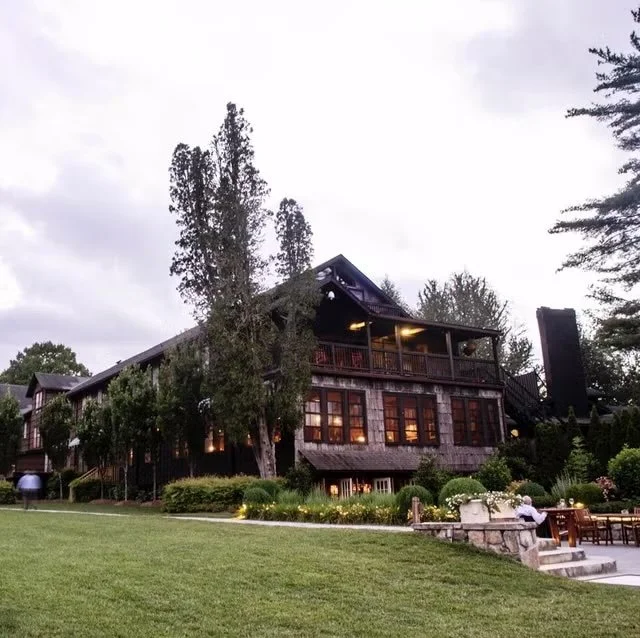 A rustic looking mountain inn surrounded by trees and shrubs.