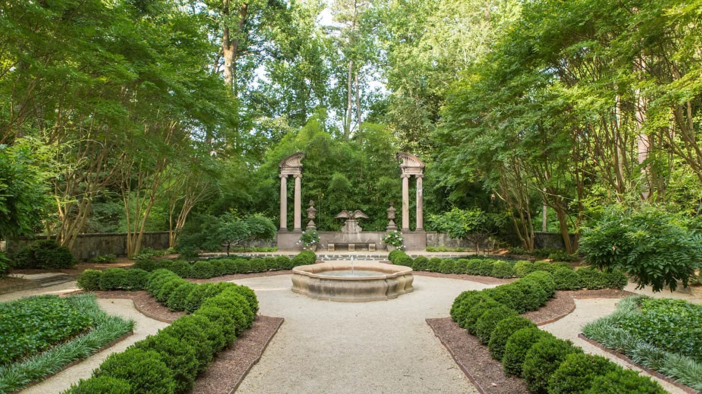 Formal gardens surrounded by trees and lined with boxwoods.