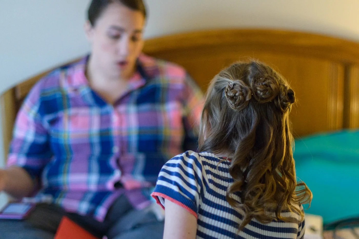 Detail of flower girl’s hair with three rosette buns and curls as she gets ready with the bride in a home in fairfax, virginia