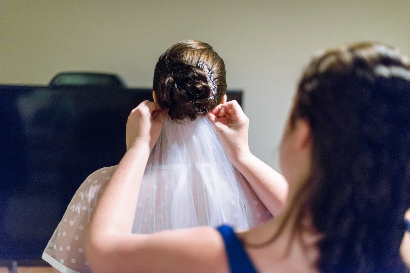 A bridesmaid puts on the bride’s veil as they get ready in fairfax, virginia