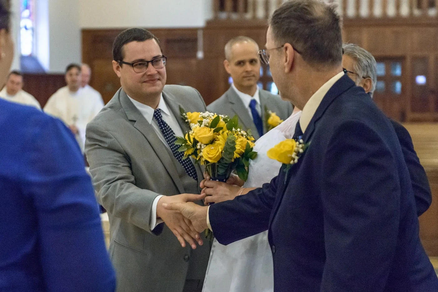 The groom shakes hands with the bride’s father during wedding ceremony at St James Catholic Church in Falls Church, Virginia