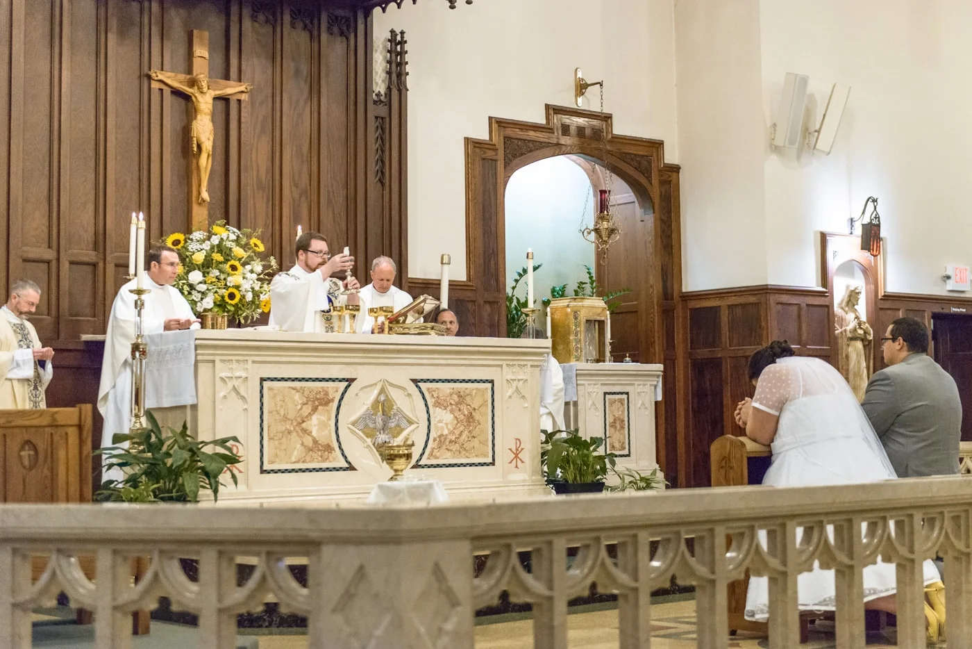 A prayerful bride and groom kneel before the altar during Catholic mass wedding ceremony at St James Catholic Church in Falls Church, Virginia