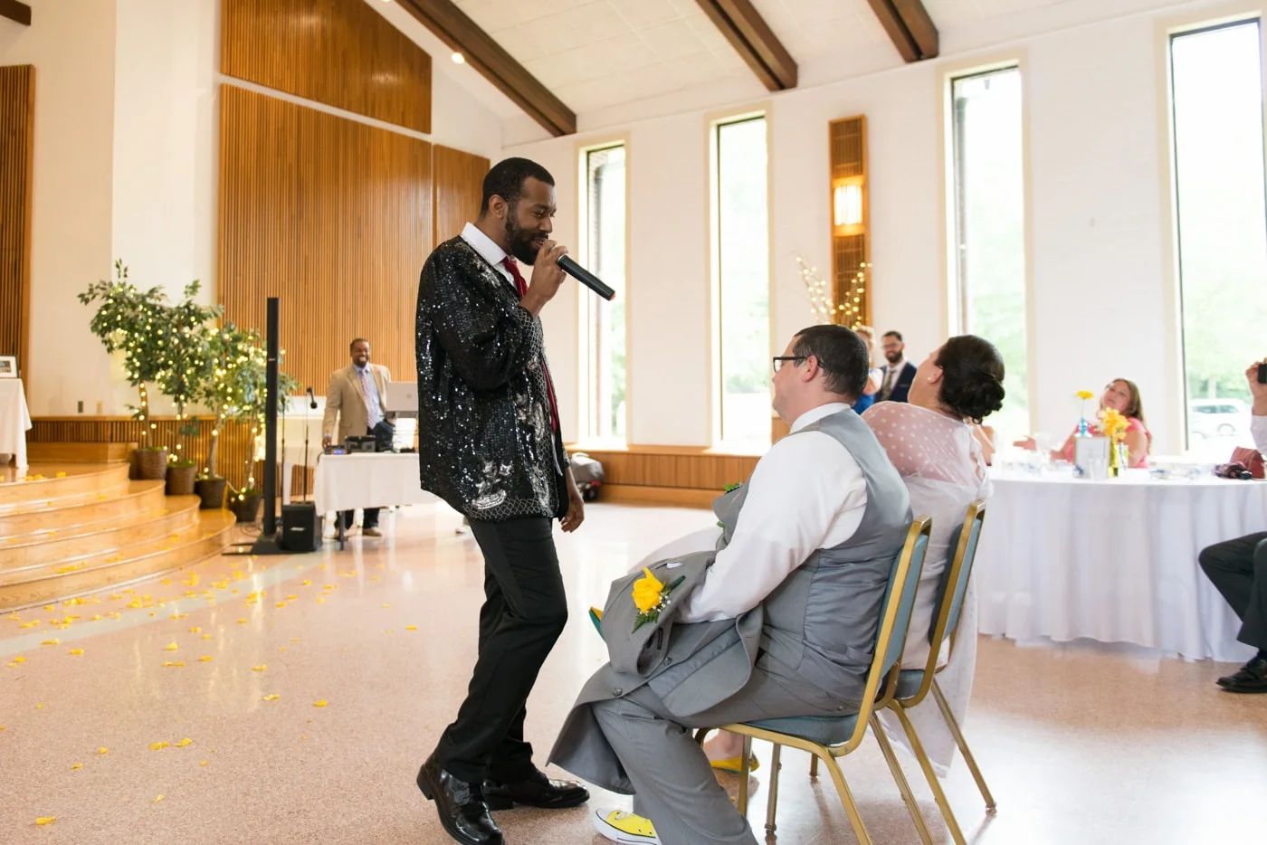 A wedding guest performs a lip sync for the seated bride and groom at St Mark Catholic Church in Vienna, Virginia