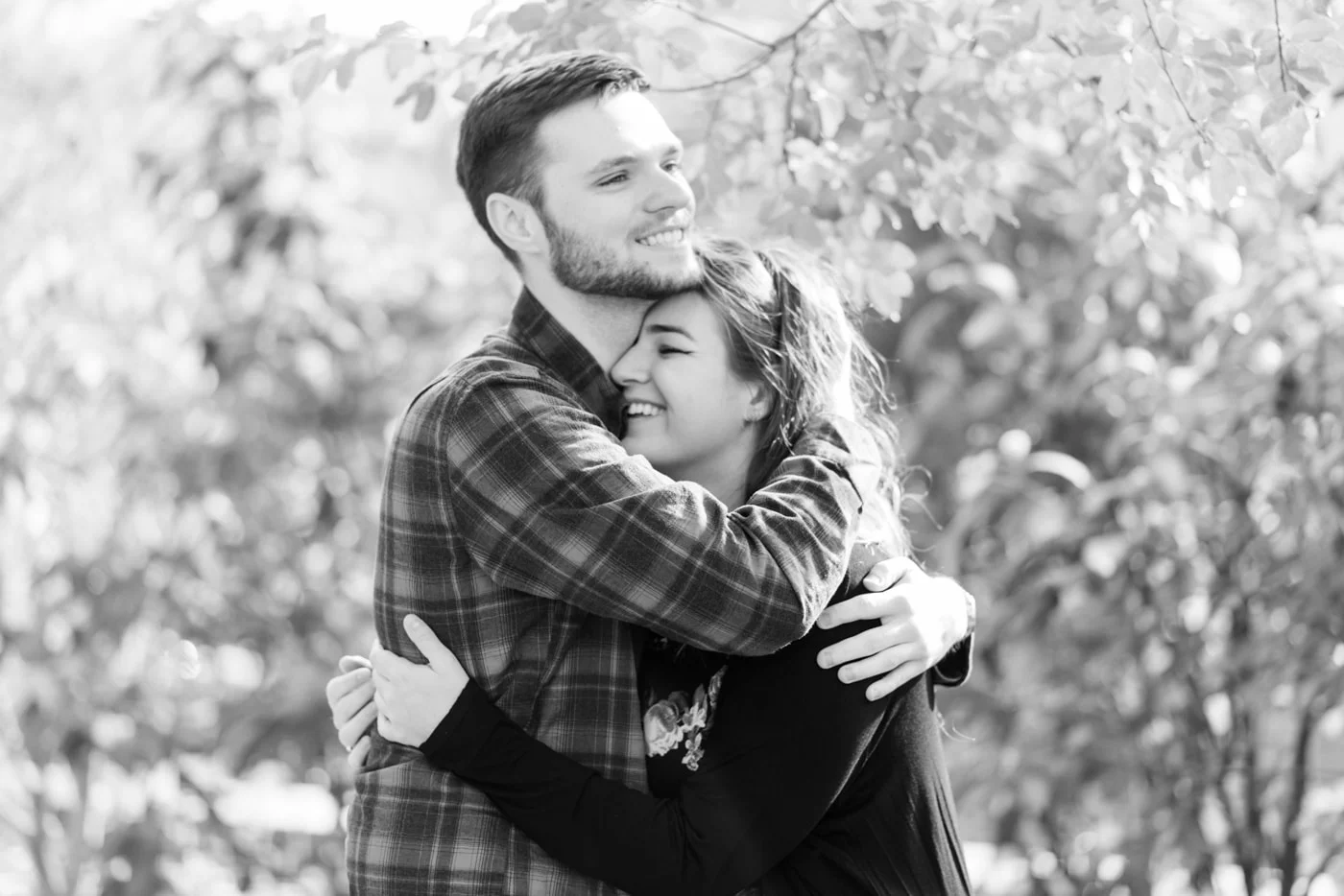 Black and white of a young couple embracing and laughing in Old Town Alexandria