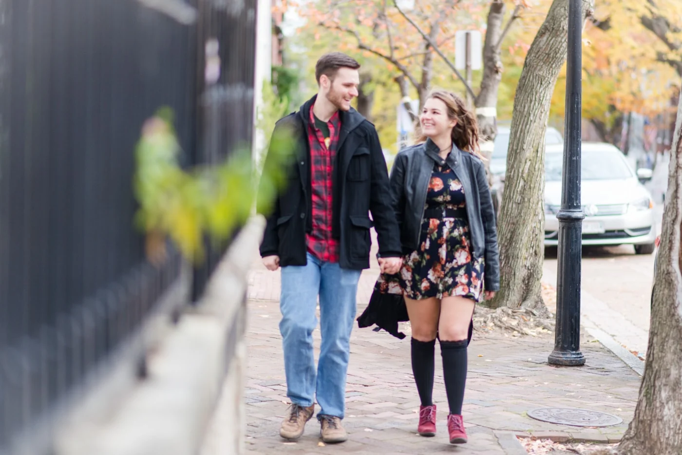 A young couple holding hands as they walk down the sidewalk in Old Town Alexandria