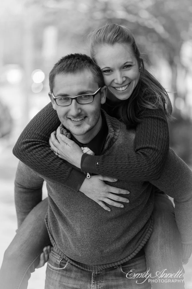 A young woman riding piggyback on her fiance as both smile at the camera in washington, dc