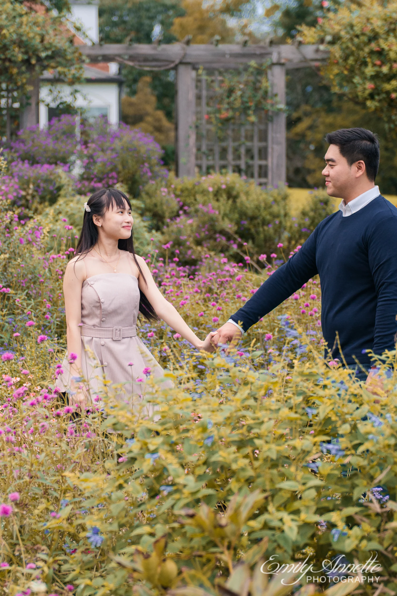 A young couple hold hands and walk through the garden at Green Spring Gardens Park in Fairfax, Virginia