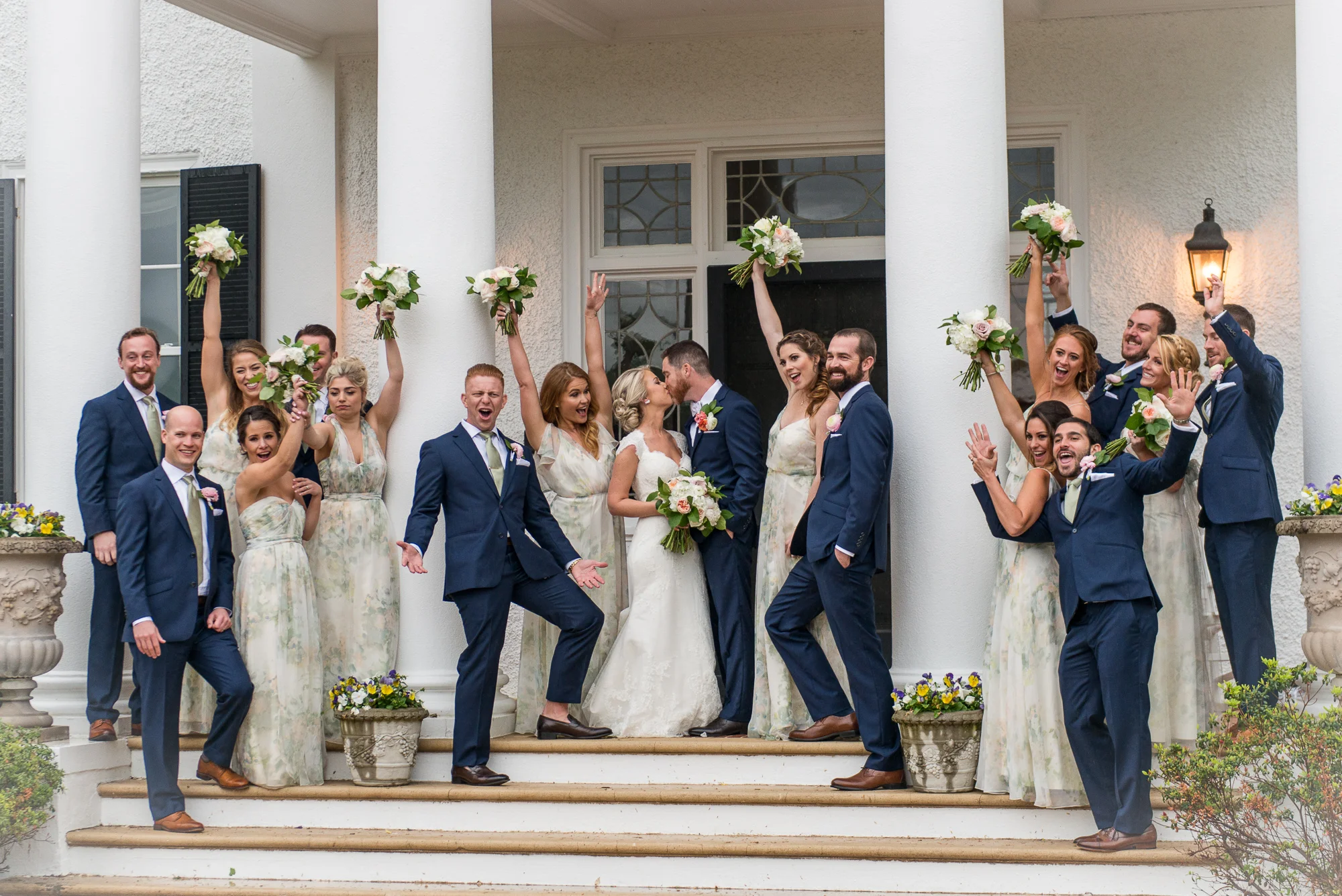 The wedding party celebrates with cheers as the bride and groom kiss outside Keswick Vineyards in Charlottesville, Virginia