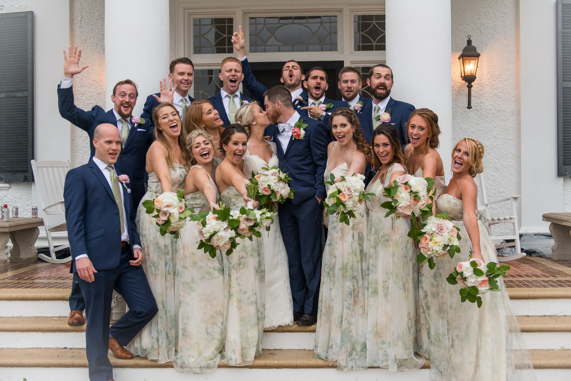 The wedding party celebrates with cheers as the bride and groom kiss outside Keswick Vineyards in Charlottesville, Virginia