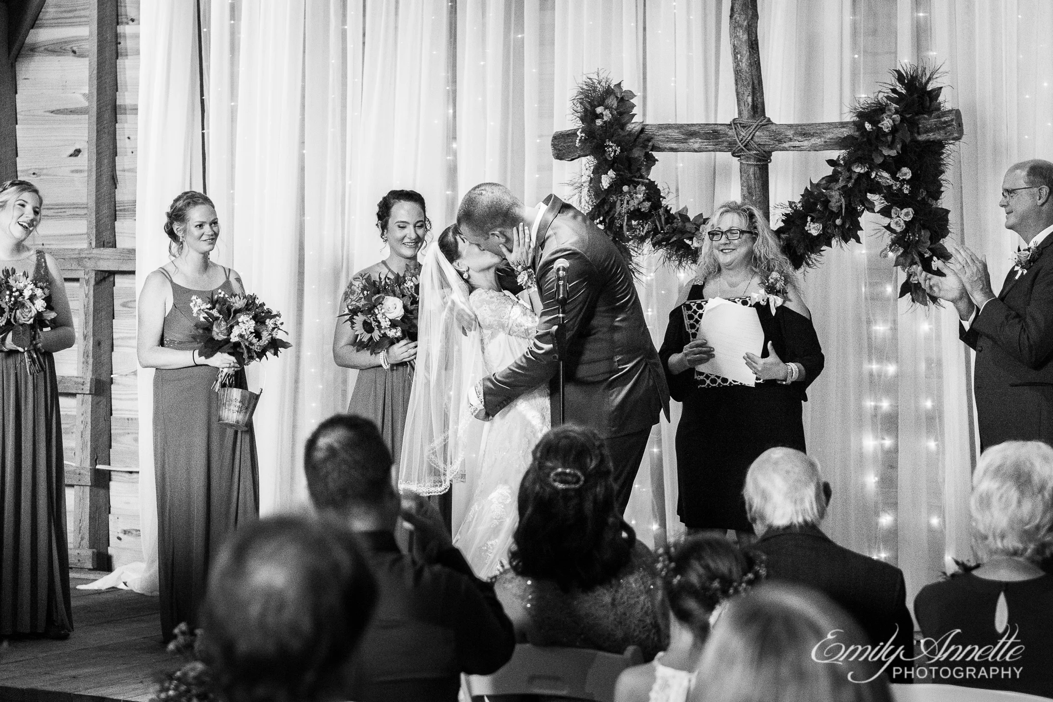 A bride and groom share their first kiss as husband and wife inside a decorated barn for a wedding ceremony during a country wedding at Amber Grove near Richmond, Virginia