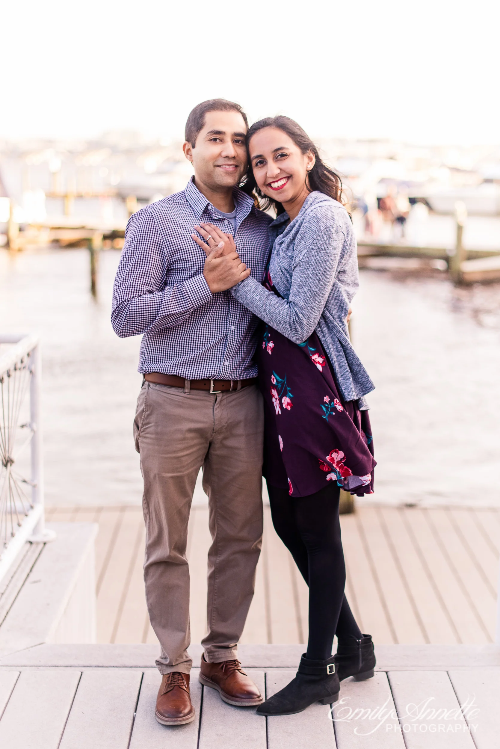 An engaged couple poses by the Potomac River docks in Old Town Alexandria Virginia for an engagement session