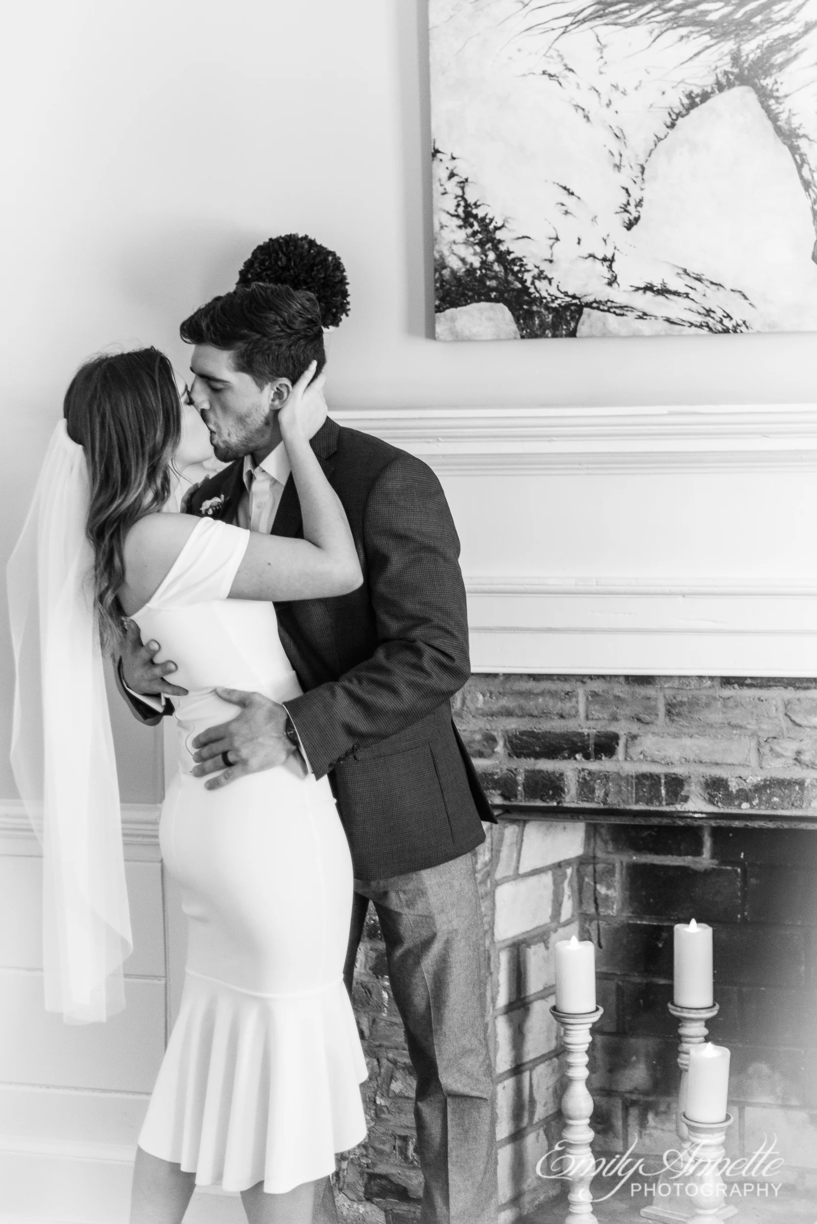 A bride and groom share a kiss while standing next to a fireplace filled with candles on their wedding day at Fleetwood Farm Winery in Leesburg, Virginia