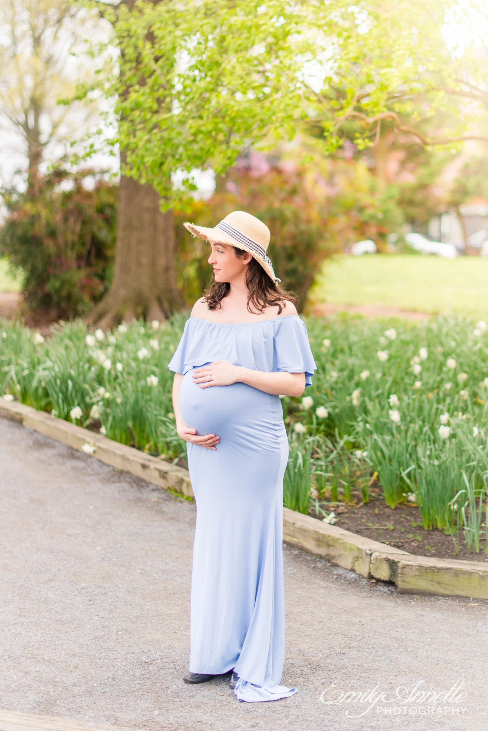 A pregnant woman poses for spring maternity photos in Old Town Alexandria wearing a romantic blue dress