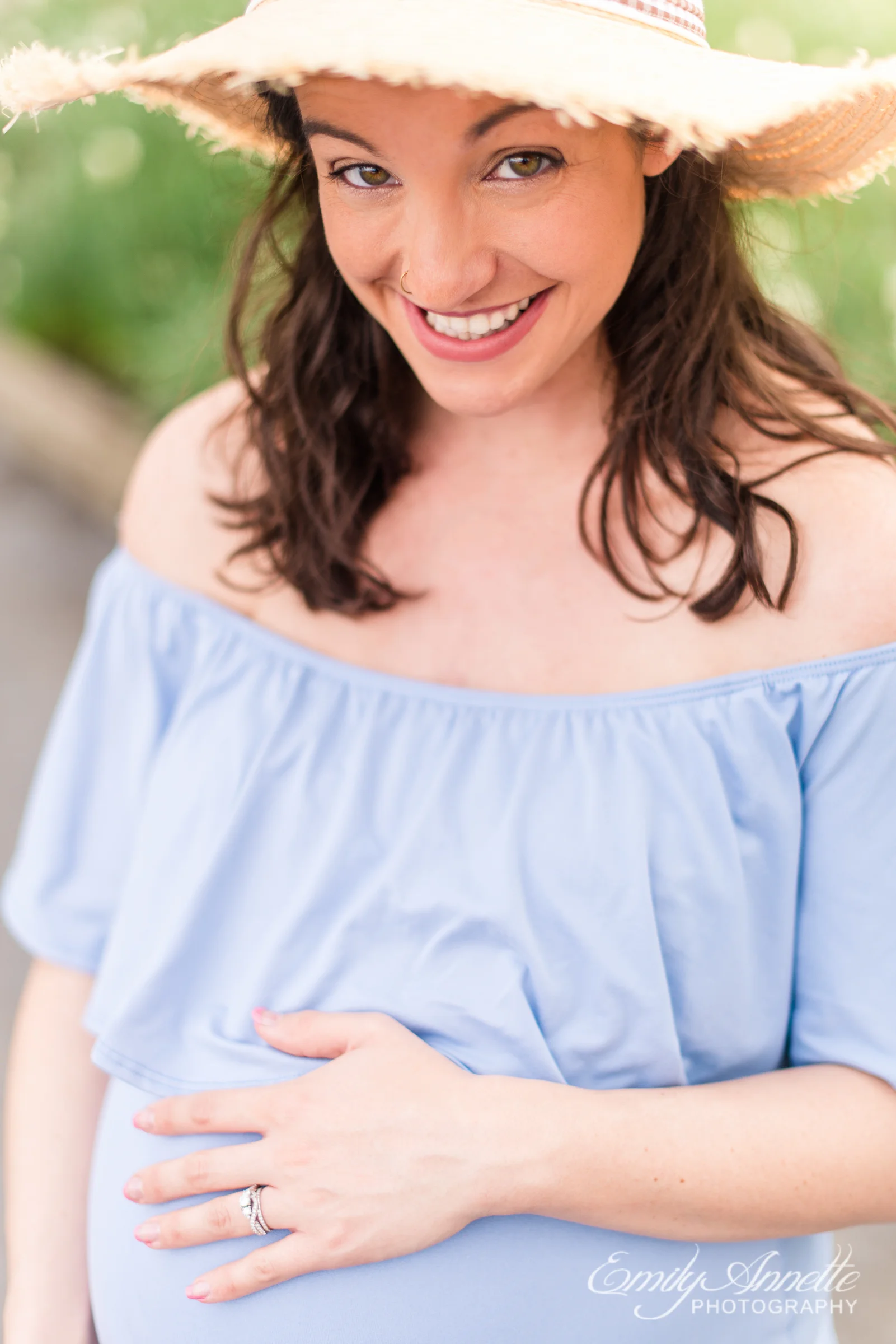 A pregnant woman poses for spring maternity photos in Old Town Alexandria wearing a romantic blue dress