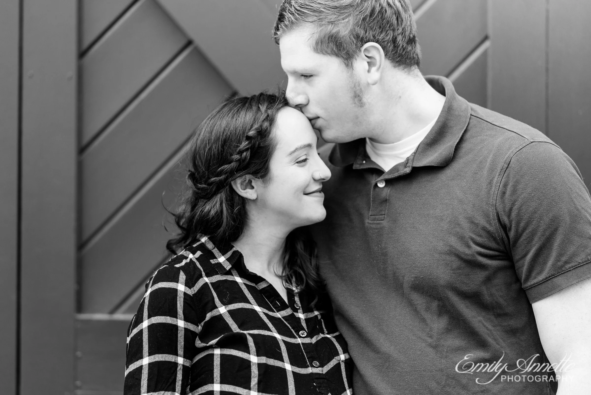 A pregnant woman poses with her husband for maternity photos in Old Town Alexandria wearing a fun casual shirt and jeans