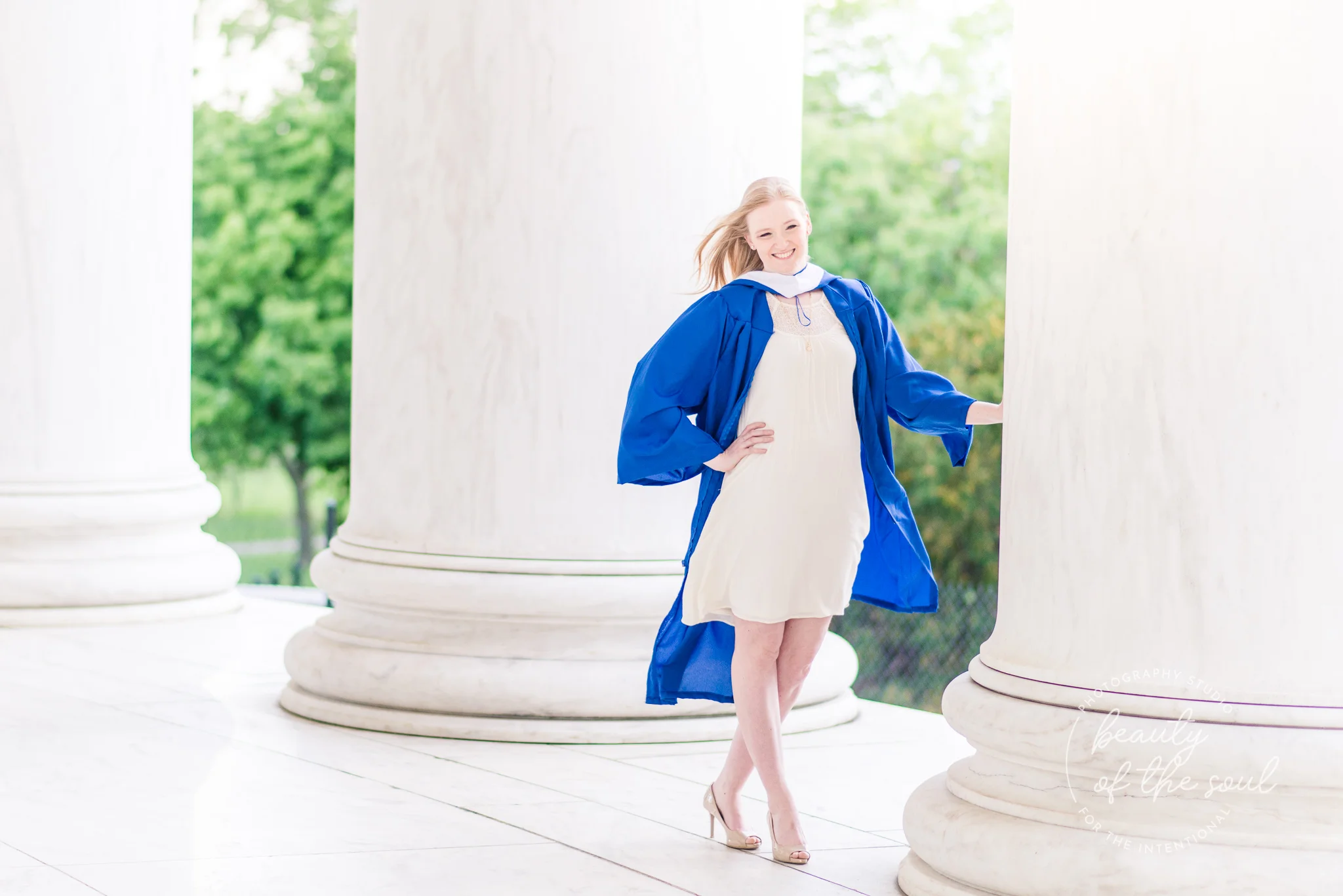 A college grad poses within the columns of the Jefferson Memorial for a Tidal Basin cap and gown session in Washington, DC before her graduation from Marymount University in Arlington, Northern Virginia