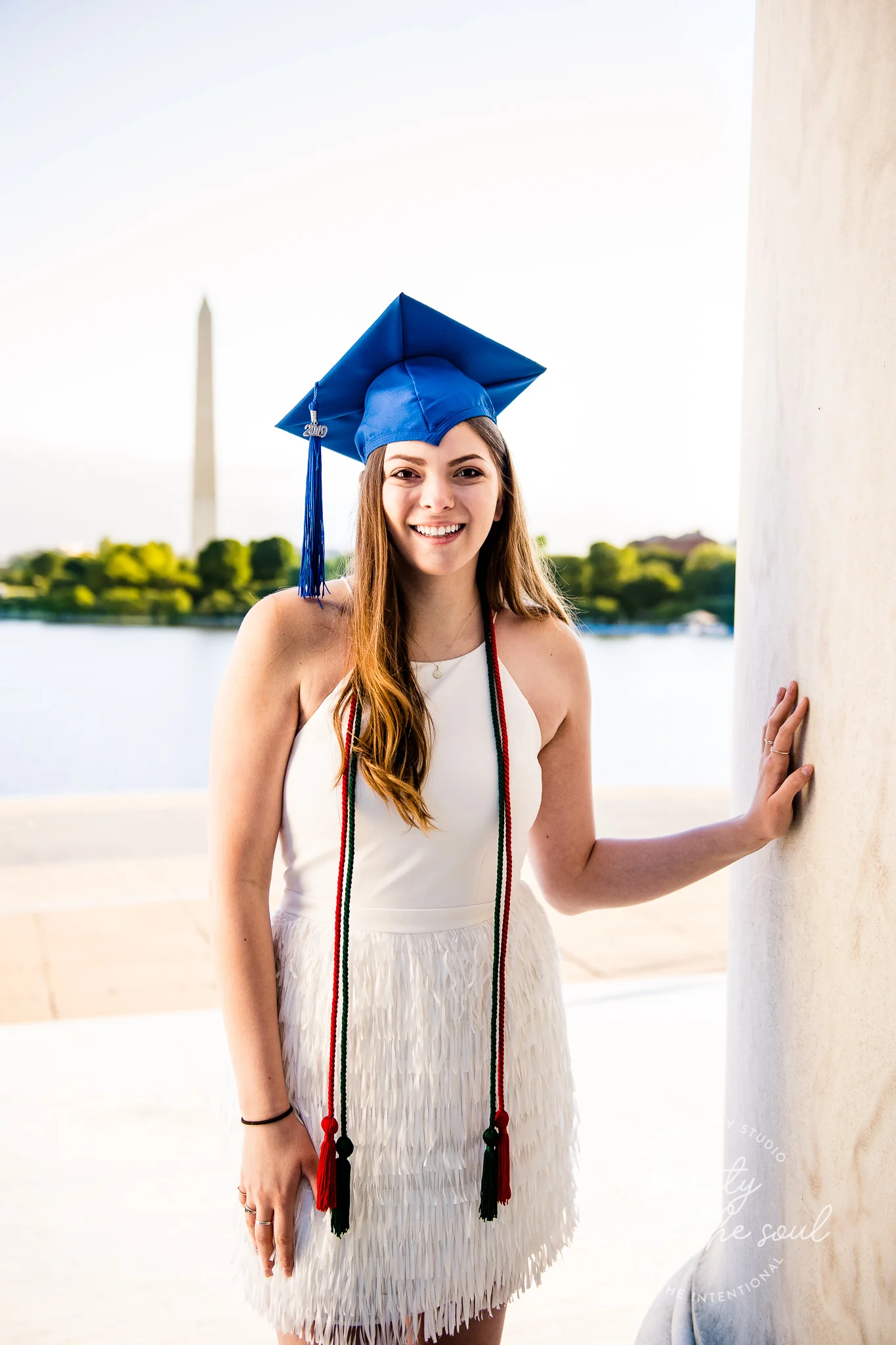 A graduate from Marymount University in Arlington, Northern Virginia standing in front of the Washington Monument at the Jefferson Memorial for her cap and gown session in Washington, DC