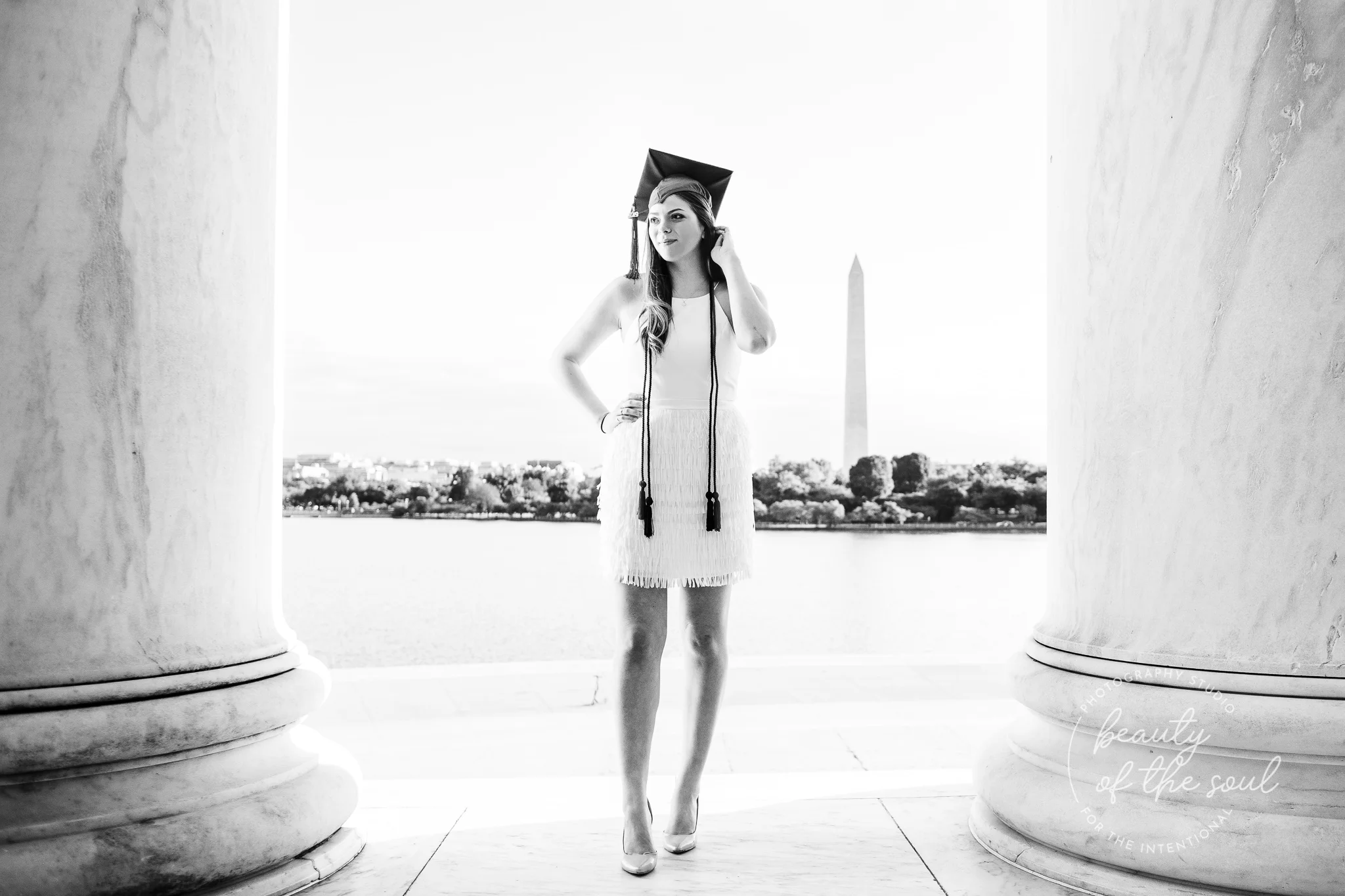 A graduate from Marymount University in Arlington, Northern Virginia standing in front of the Washington Monument at the Jefferson Memorial for her cap and gown session in Washington, DC