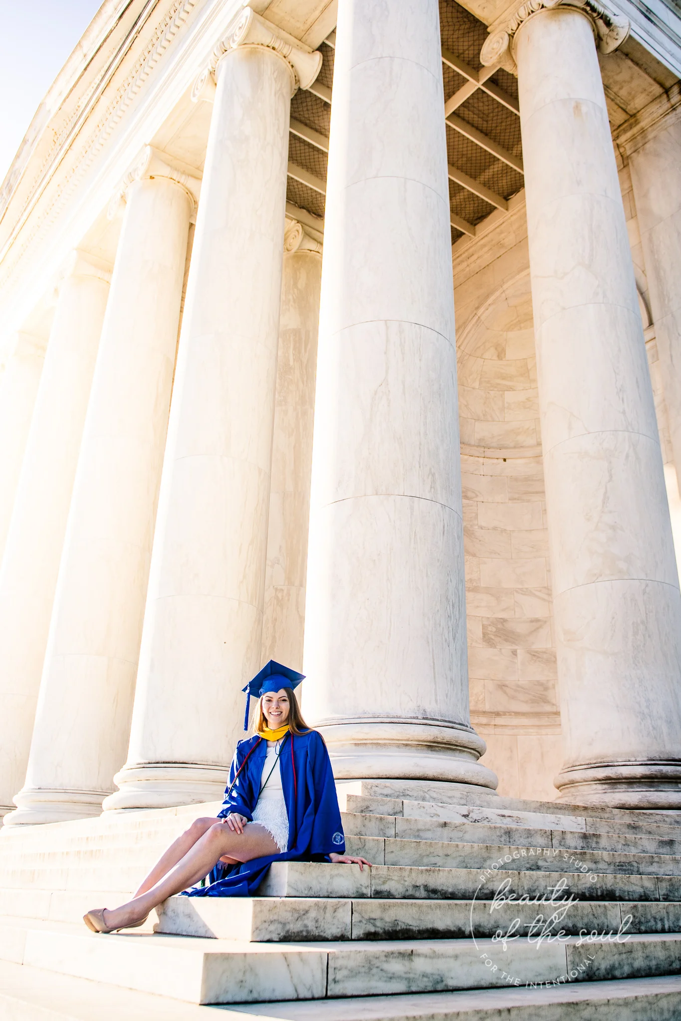 A graduate from Marymount University in Arlington, Northern Virginia sitting on the steps of the Jefferson Memorial for her cap and gown session in Washington, DC