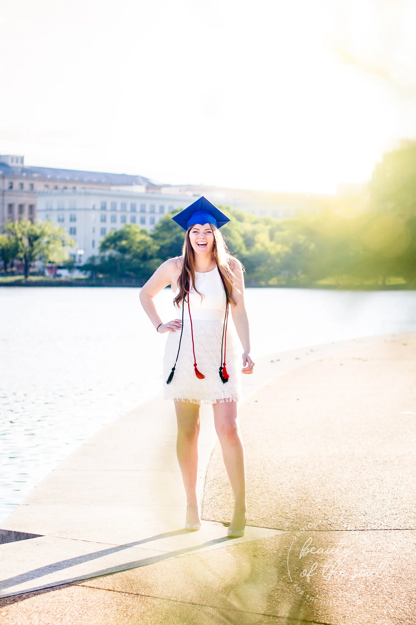 A graduate from Marymount University in Arlington, Northern Virginia standing beside the Potomac River at the Tidal Basin for her cap and gown session in Washington, DC