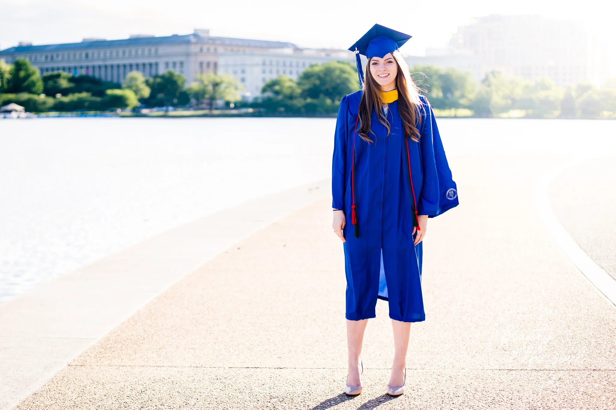 A graduate from Marymount University in Arlington, Northern Virginia standing beside the Potomac River at the Tidal Basin for her cap and gown session in Washington, DC