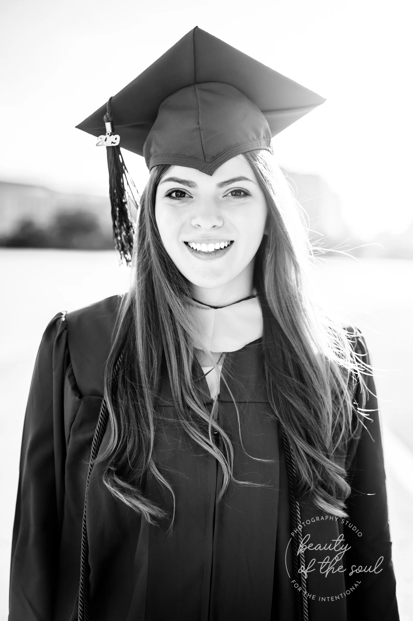 A graduate from Marymount University in Arlington, Northern Virginia standing beside the Potomac River at the Tidal Basin for her cap and gown session in Washington, DC