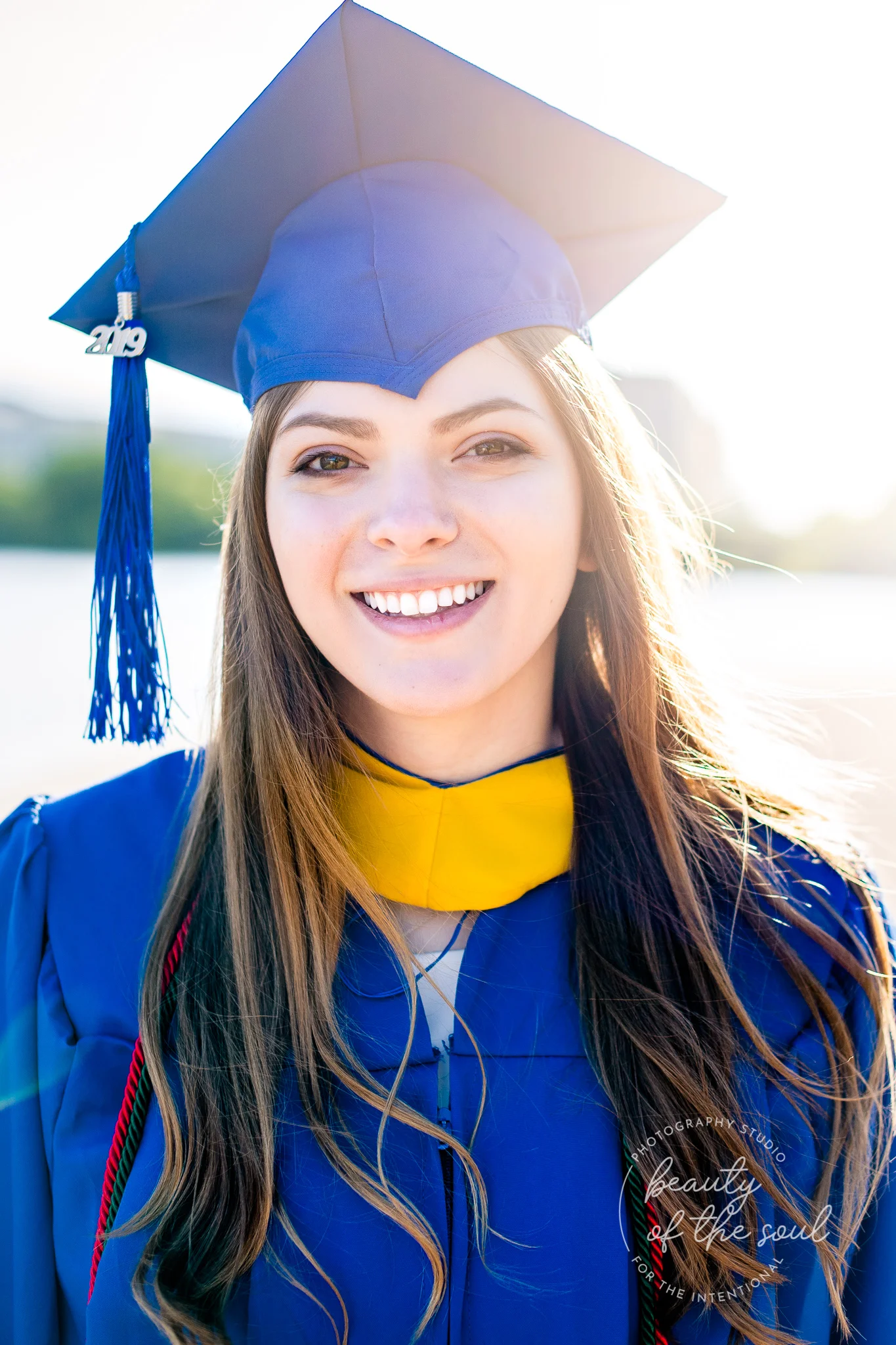 A graduate from Marymount University in Arlington, Northern Virginia standing beside the Potomac River at the Tidal Basin for her cap and gown session in Washington, DC