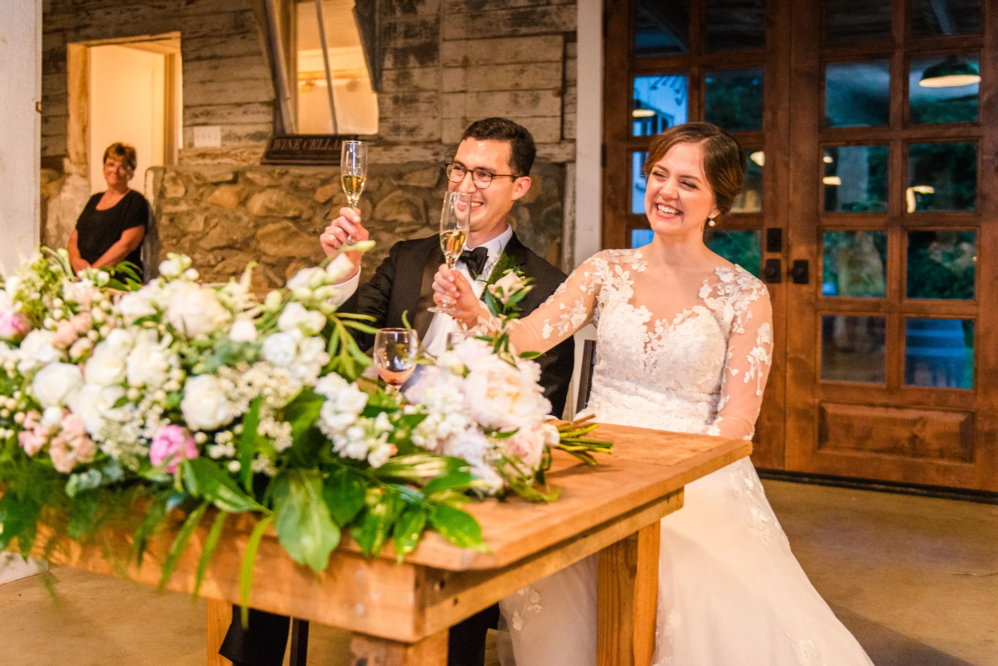 A bride and groom laugh as they raise their champagne glasses for the toasts during their wedding reception at The Barns at Hamilton Station Vineyards in Leesburg, Northern Virginia