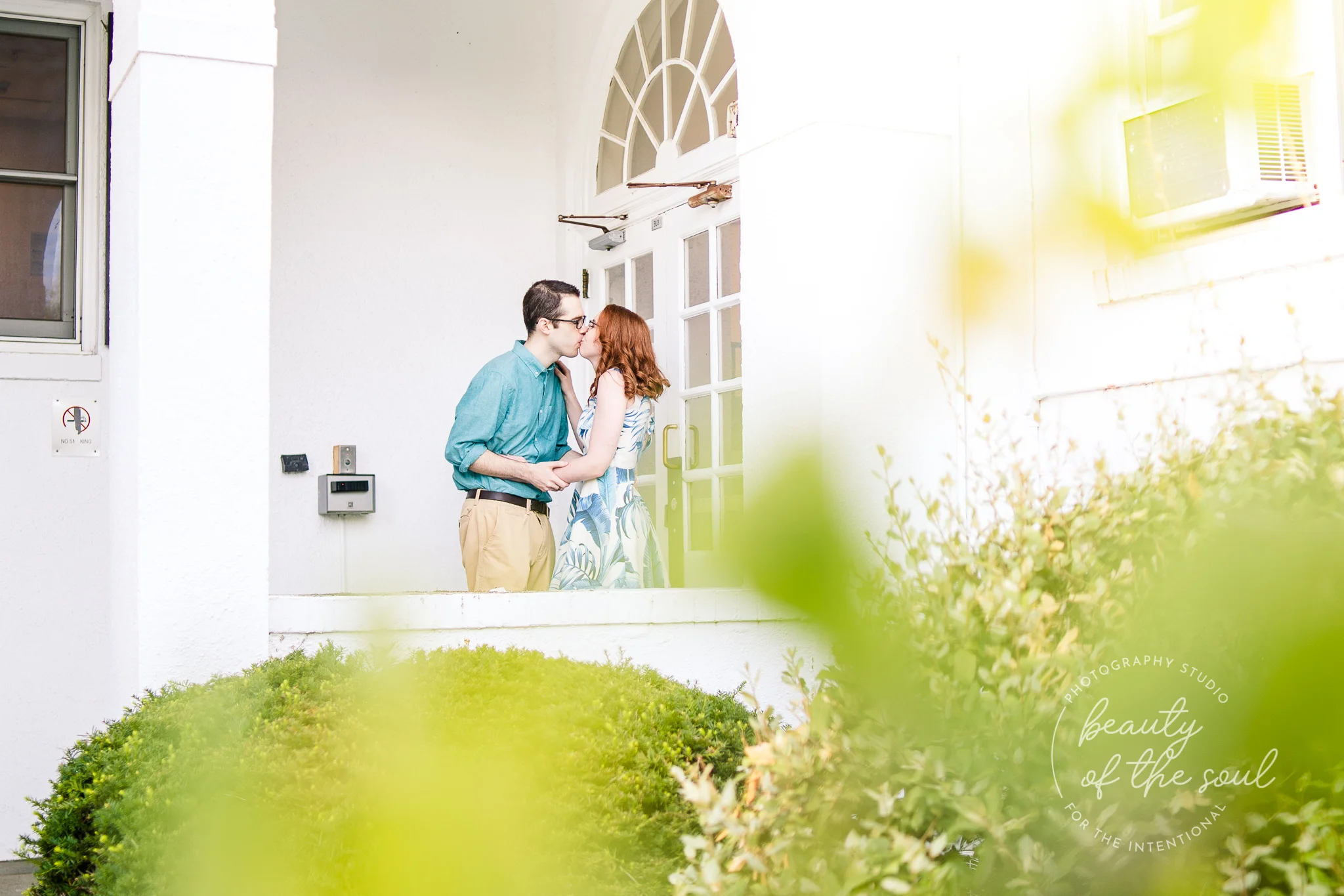 An engaged couple shares a kiss during their summer engagement session at Marymount University in Arlington, Northern Virginia