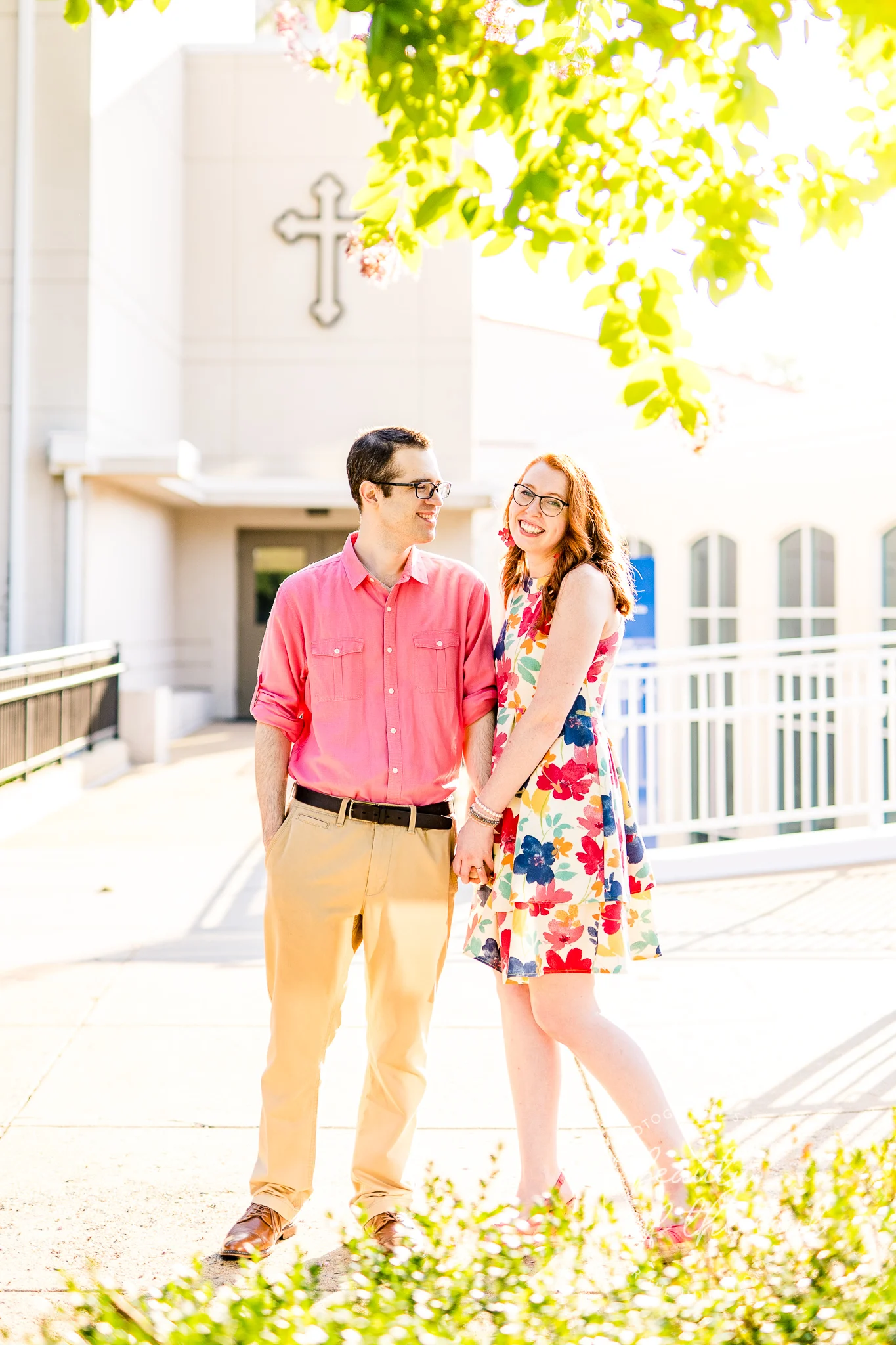 An engaged couple stand together in front of Gailhac Hall at Marymount University during their summer sunrise engagement session in Arlington, Northern Virginia
