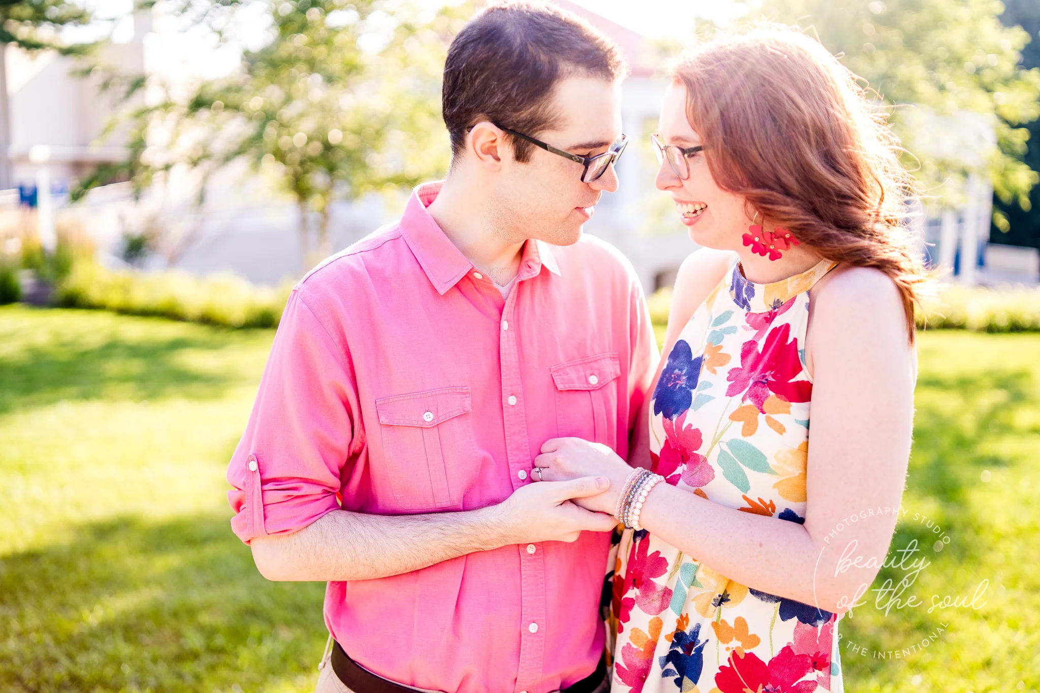 An engaged couple hold hands and look at each other on Ireton Lawn at Marymount University during their summer sunrise engagement session in Arlington, Northern Virginia
