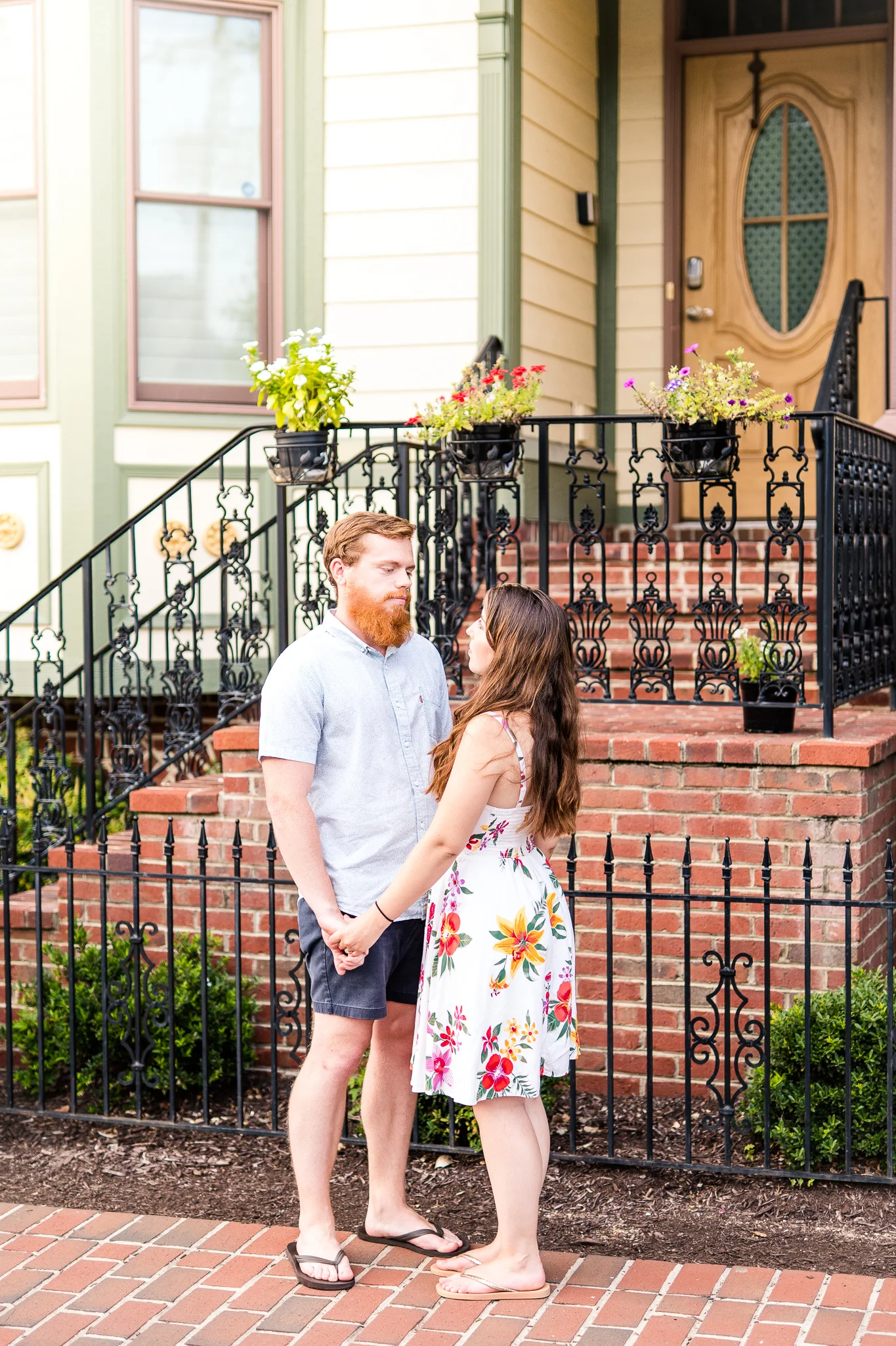 A couple holds hands during their summer sunset engagement session in Historic Occoquan, Northern Virginia